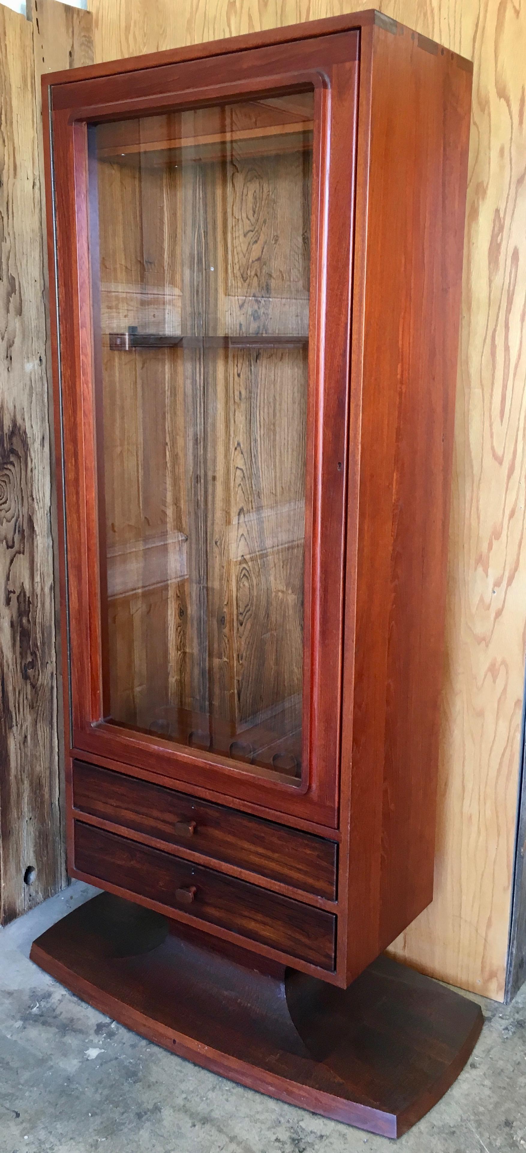 Sculpted walnut pedestal gun/ trophy cabinet with rosewood and maple accents. Locking glass door for security, signed on base
Expert joinery by master craftsman John Nyquist
Case dimensions 30 L x 16.5 D
Base dimensions 42