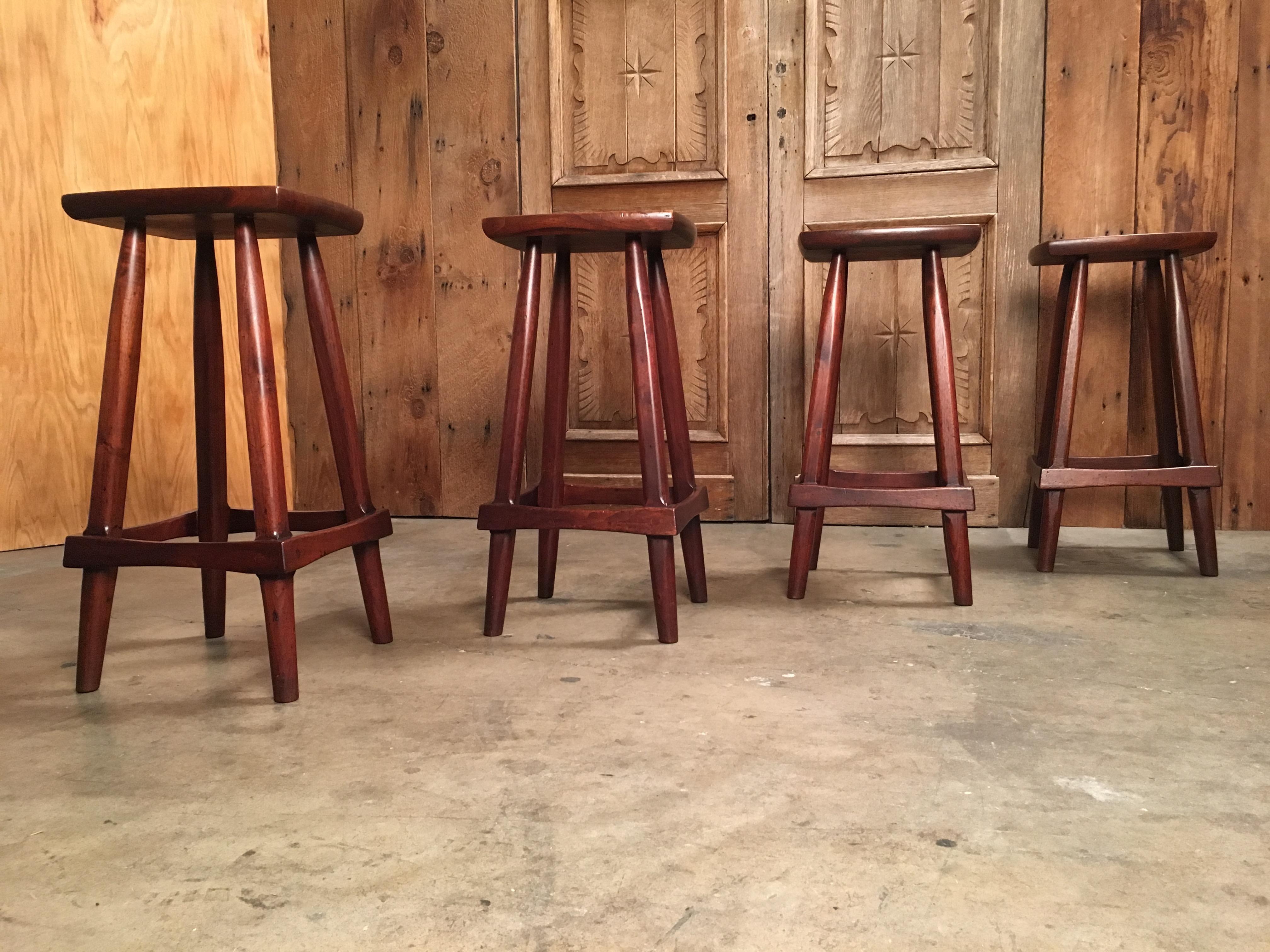 Set of four vintage counter height solid walnut stools with tapered legs and bowtie footrest.
