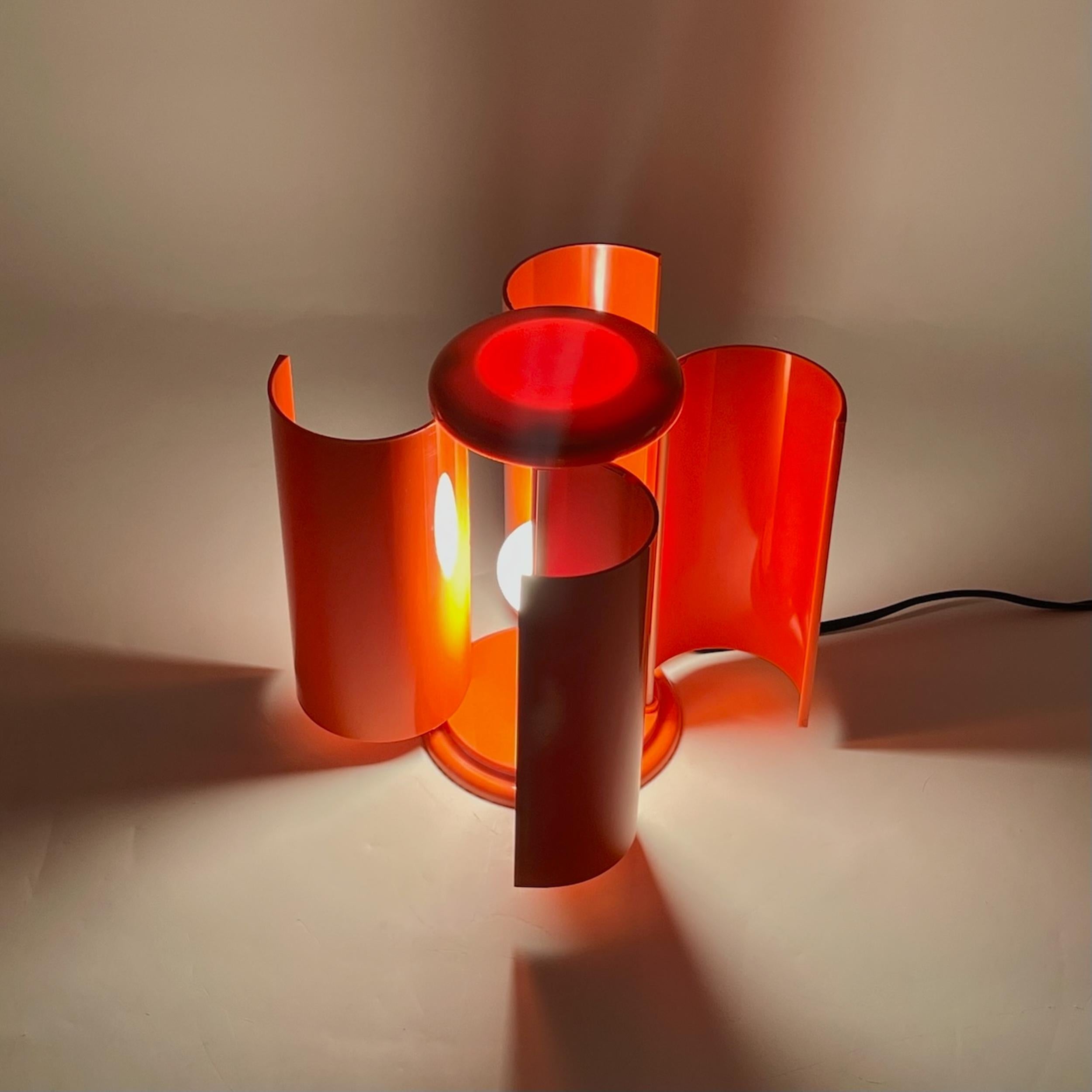 The Studio D.A. Lamperti Orange Lamp is a refined blend of elegance and innovation from Italy’s golden era of design. Crafted in vibrant orange plastic, its base supports a sophisticated arrangement of four metal rods and a delicately curved,