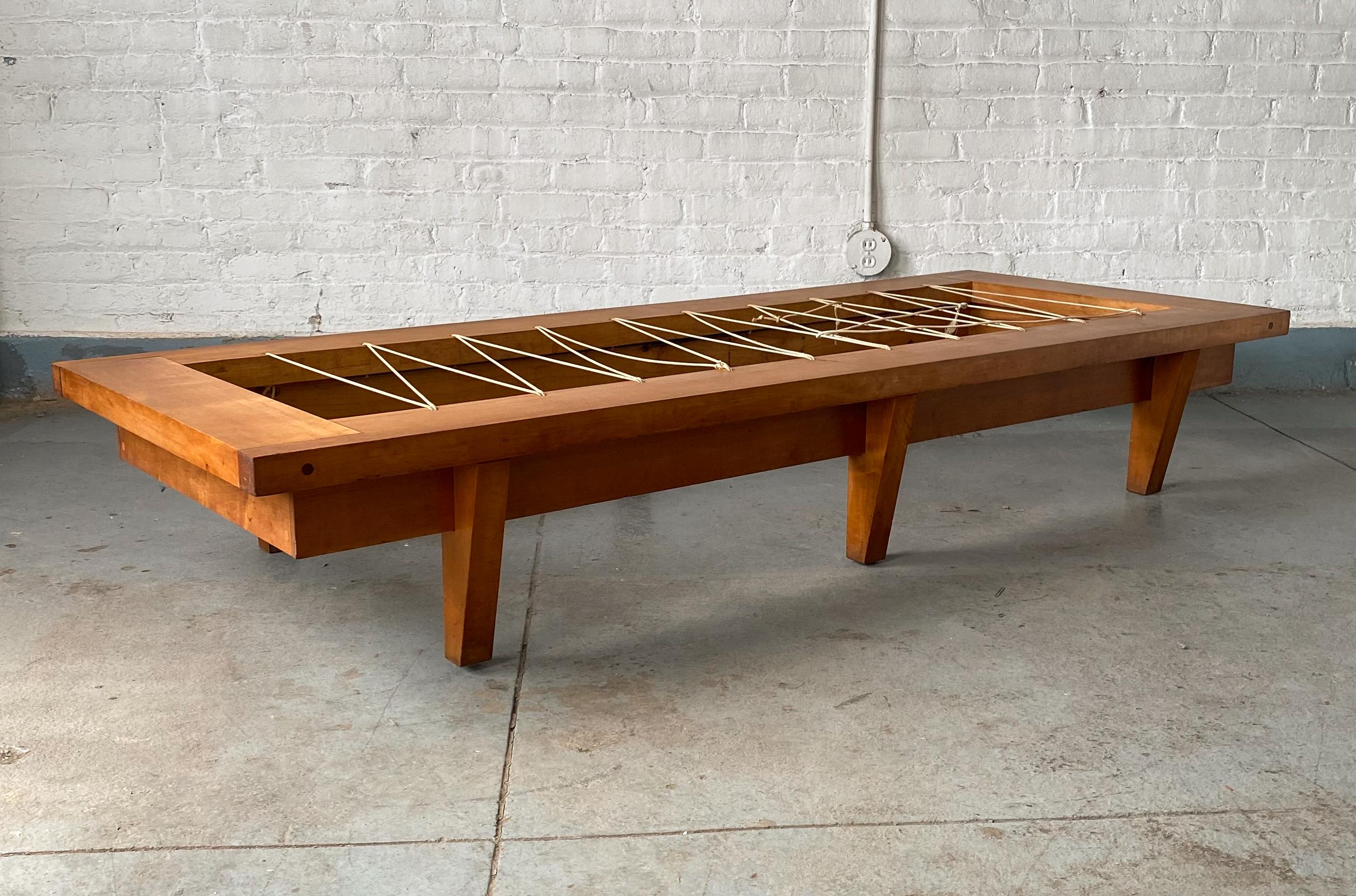 Soundly built and nicely proportioned daybed of solid maple with exposed dowel joints and an architectural bearing to the overhanging top and the angled legs. A studio production, circa 1970's, likely from the Northeast region. Zig-zag string