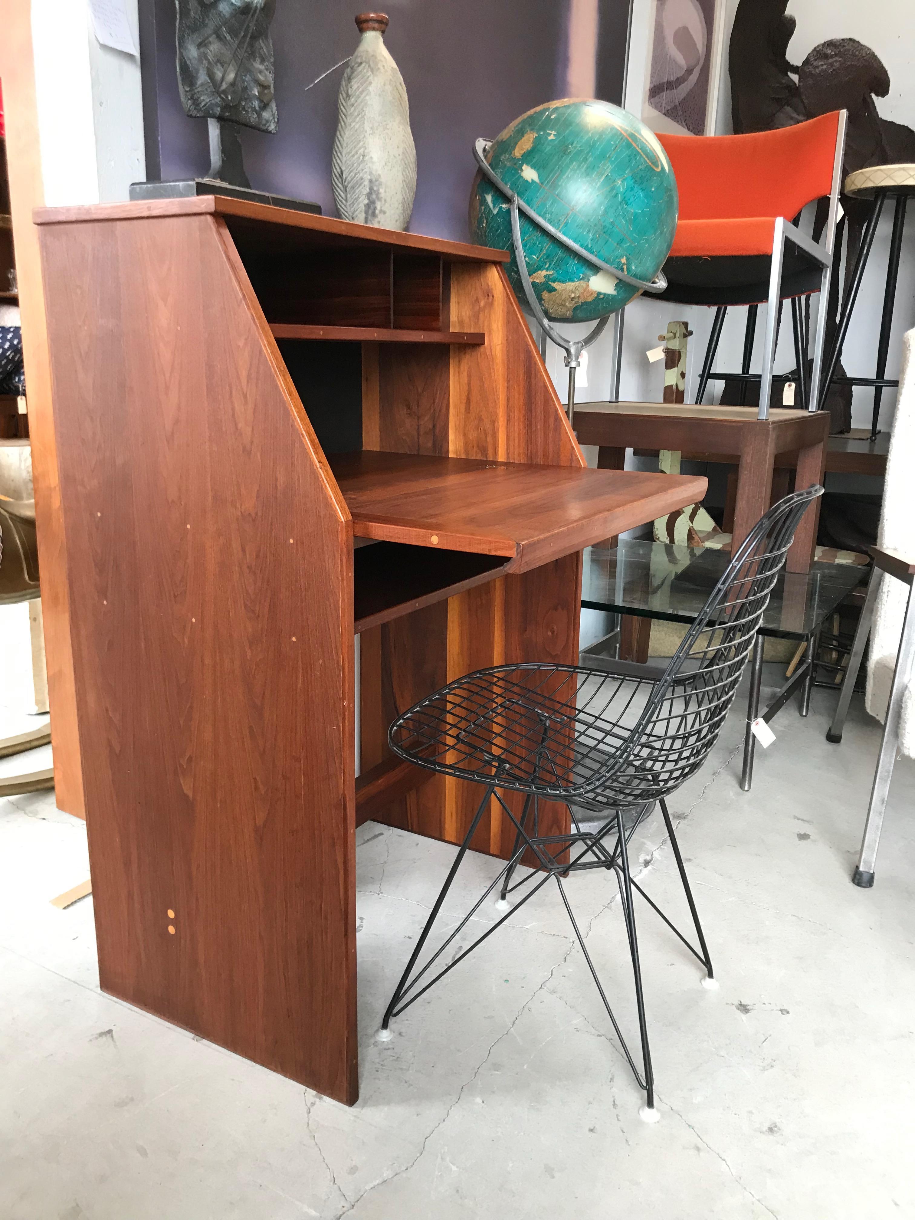 Nice modernist design.
It appears to be a custom one-off.
Plywood with walnut veneer and trim with solid walnut base support. 
Sculpted walnut pull.
Nice storage compartments with bottom shelf. 
Original vintage condition with a nice