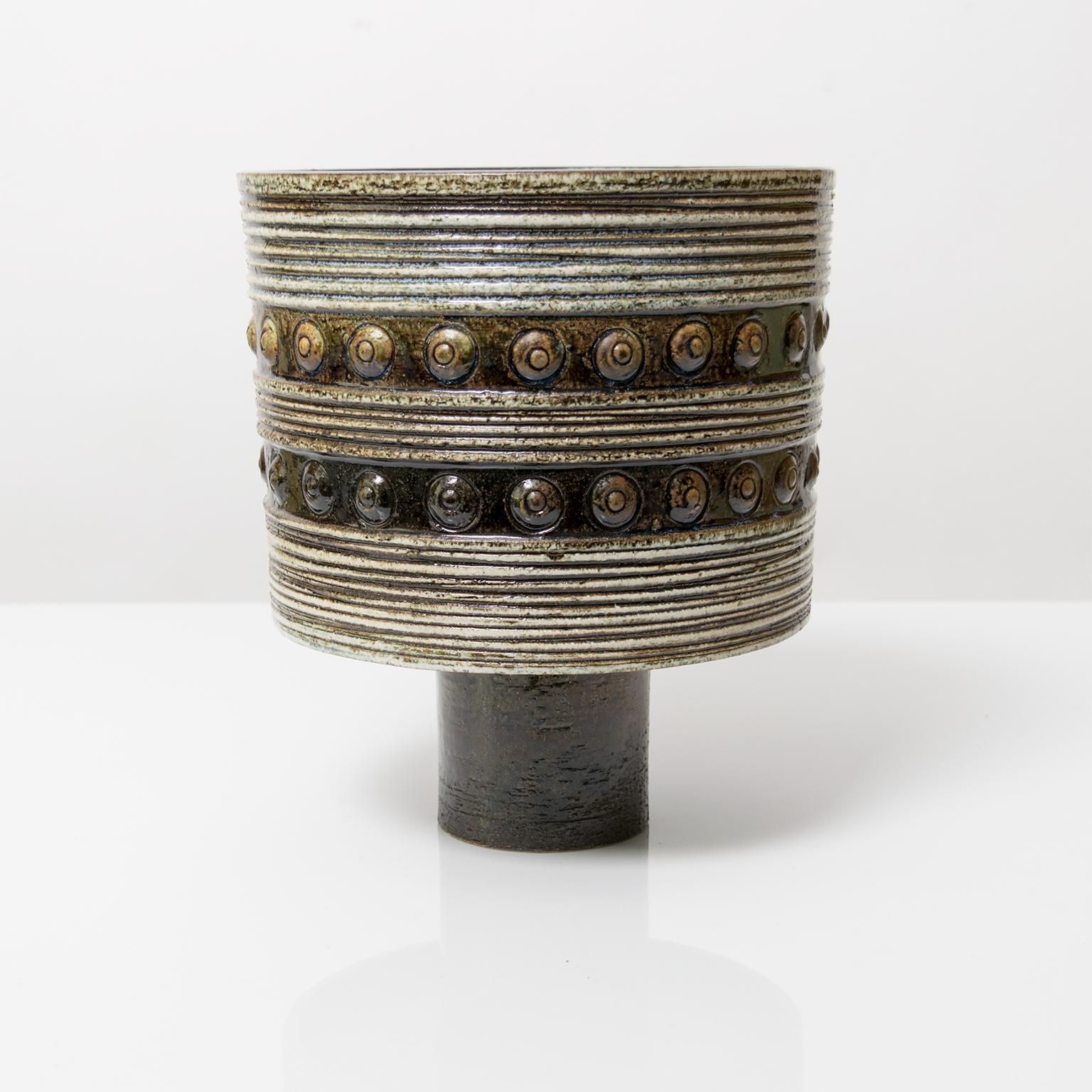 A large Scandinavian Modern studio footed bowl or vase by Britt-Louise Sundell for Gustavsberg, circa 1960. This piece is highly textured with horizontal grooves, circles and glazed in earthy, neutral colors and a deep blue inside.

Measures: