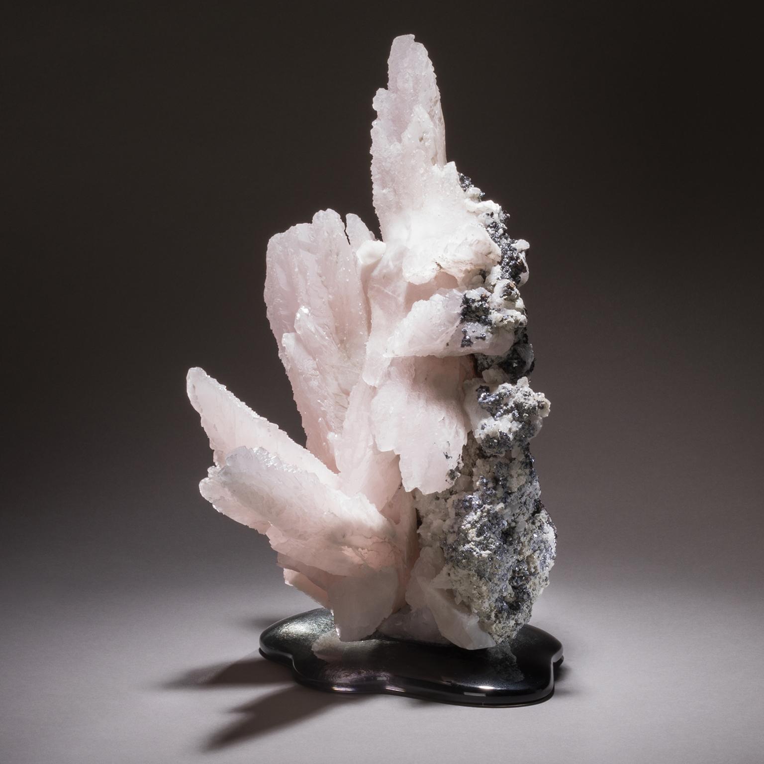 Manganoan Calcite on Cast Glass

The soothing pink hue of manganoan calcite bursts forth from a gently shaped hand cast glass base in this stunning natural sculpture from Studio Greytak. The natural points and color variations invite the viewer to