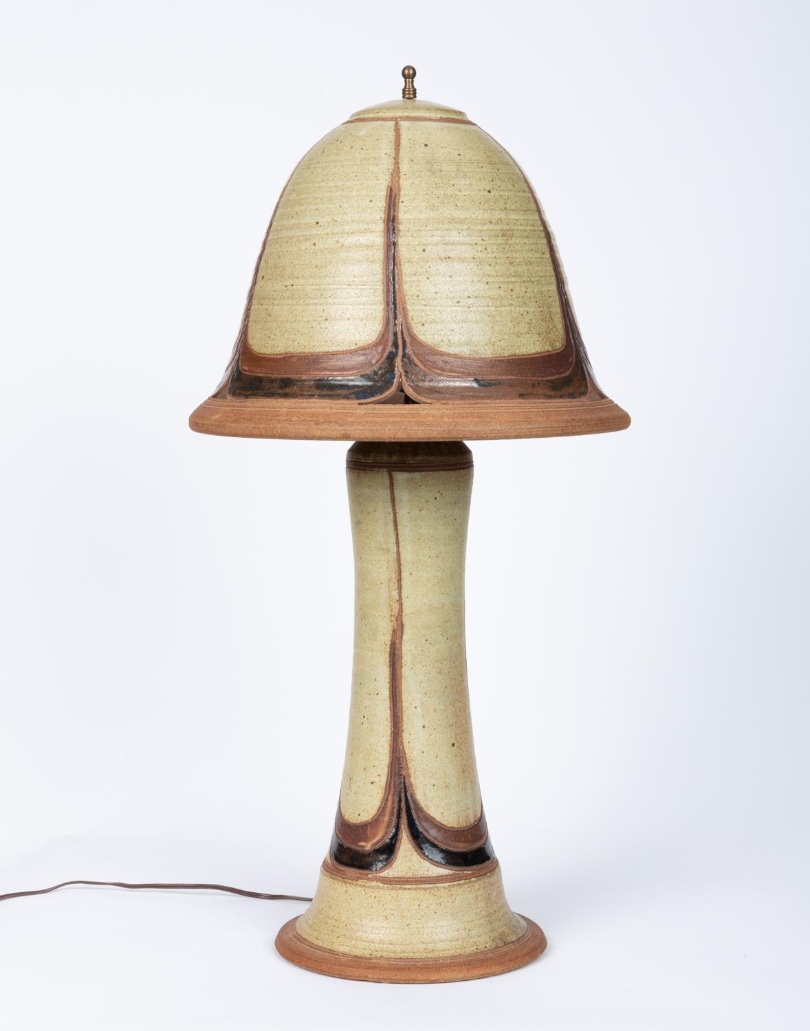 This studio lamp is like a scene in a Lewis Carroll book come to life. Made of stoneware clay and finished in stone matte glaze with brown and black glaze marble detailing along the base of the lamp and the edge of the shade. Neutral color scheme