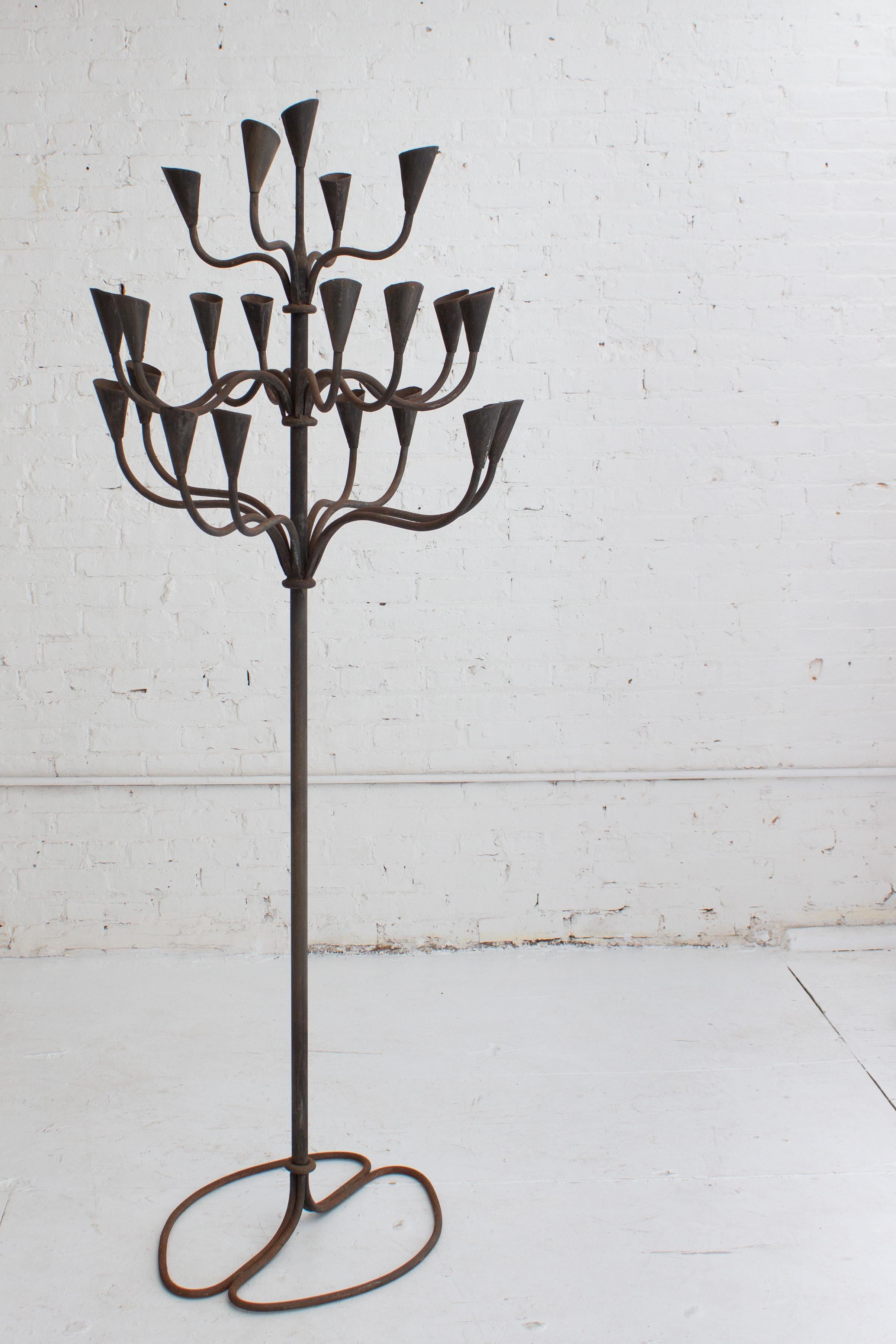 A handcrafted iron candelabra. Impressive in height scale the candelabra features 21 inserts for tapers of varying sizes. Weld marks and variations show the artists hand.
