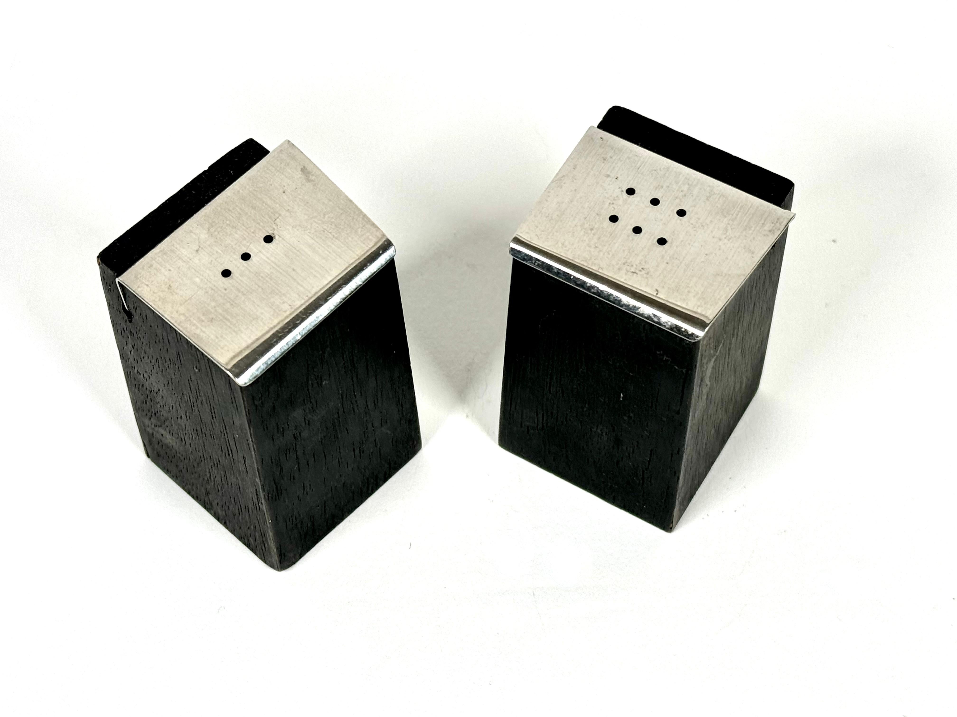 Hand crafted salt and pepper shakers by Bay Area artist Milton Cavagnaro, he was a jeweler, painter and craft maker such as these shakers for example. Black wooden bodies in a modernist form with asymmetric stainless steel tops. Cavagnaro's work was