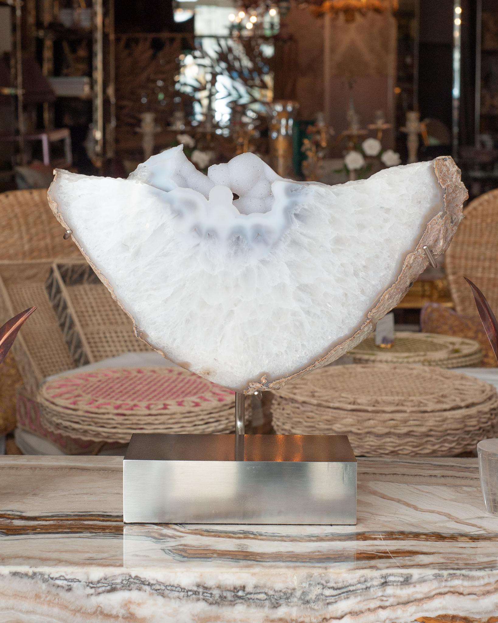 This gorgeous large Studio Maison Nurita mounted mineral slice is a stunning blend of white quartz and agate, creating a visually captivating and energetically powerful piece. The natural patterns and translucent qualities of the quartz and agate