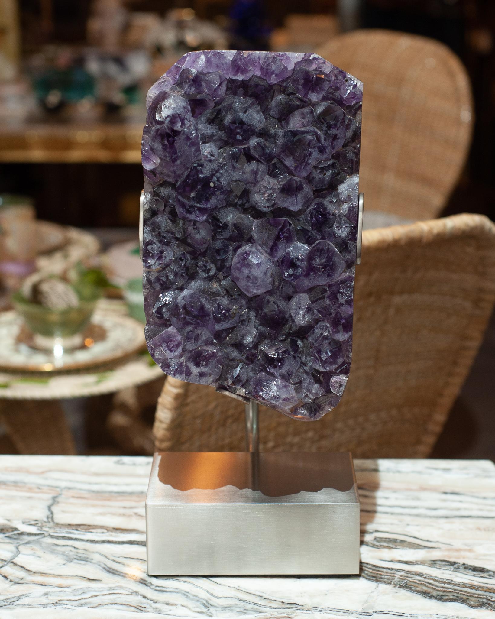 A gorgeous large amethyst specimen mounted on a custom brushed nickel base by Studio Maison Nurita. A natural thick piece of amethyst is suspended by the specialized mounting, creating both an energetic and highly decorative interior item for the