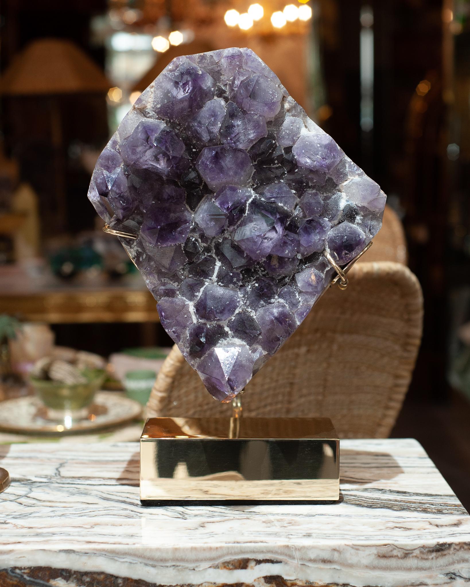 A gorgeous massive amethyst specimen mounted on a custom polished brass base by Studio Maison Nurita. A natural thick piece of amethyst is suspended by the specialized mounting, creating both an energetic and highly decorative interior item for the