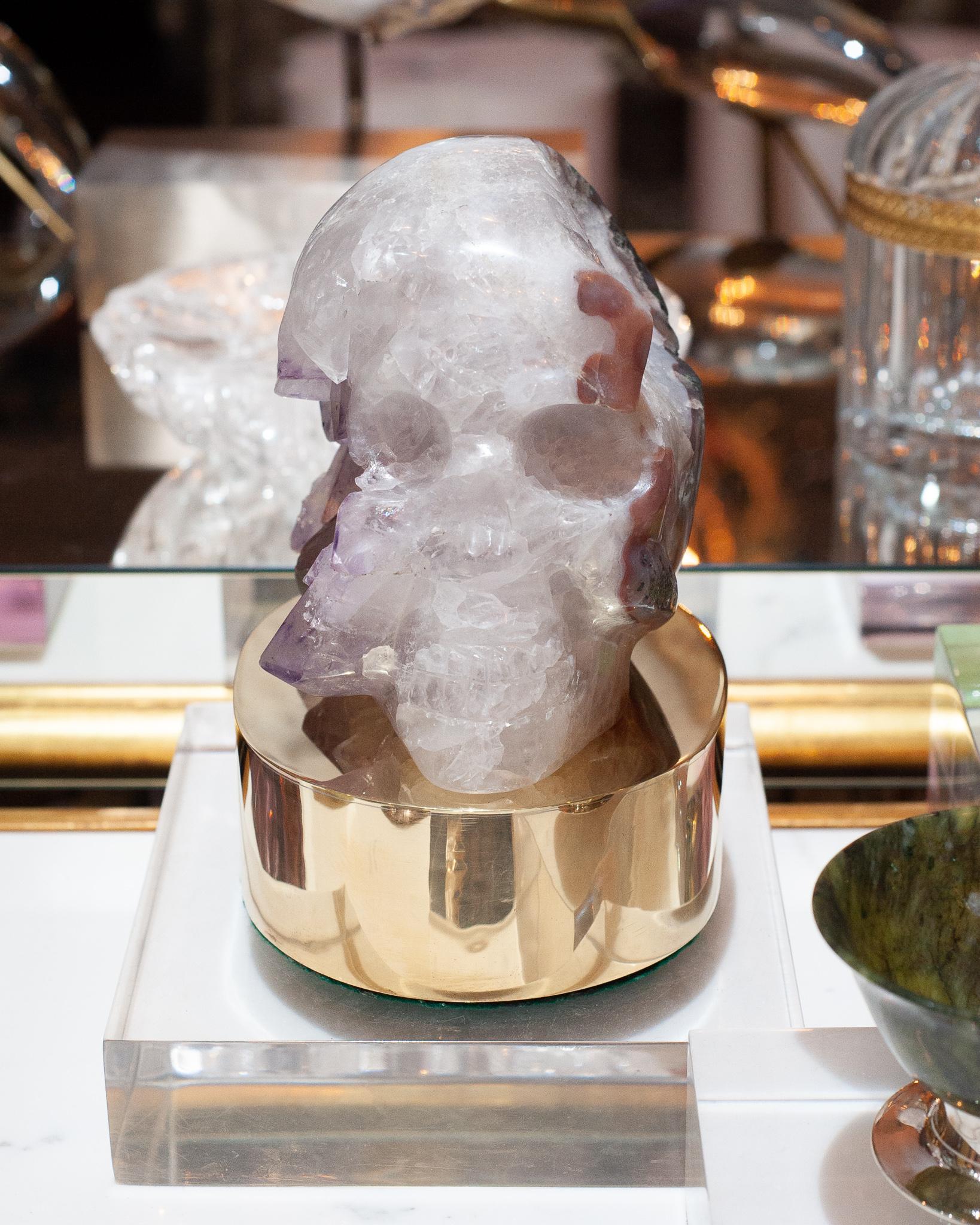 A Studio Maison Nurita large and unusual skull carving in white quartz with amethyst points, resting on a custom made polished brass base. The attractive quality of this sculpture is its size and subtle carving style. From the appropriate angle, it