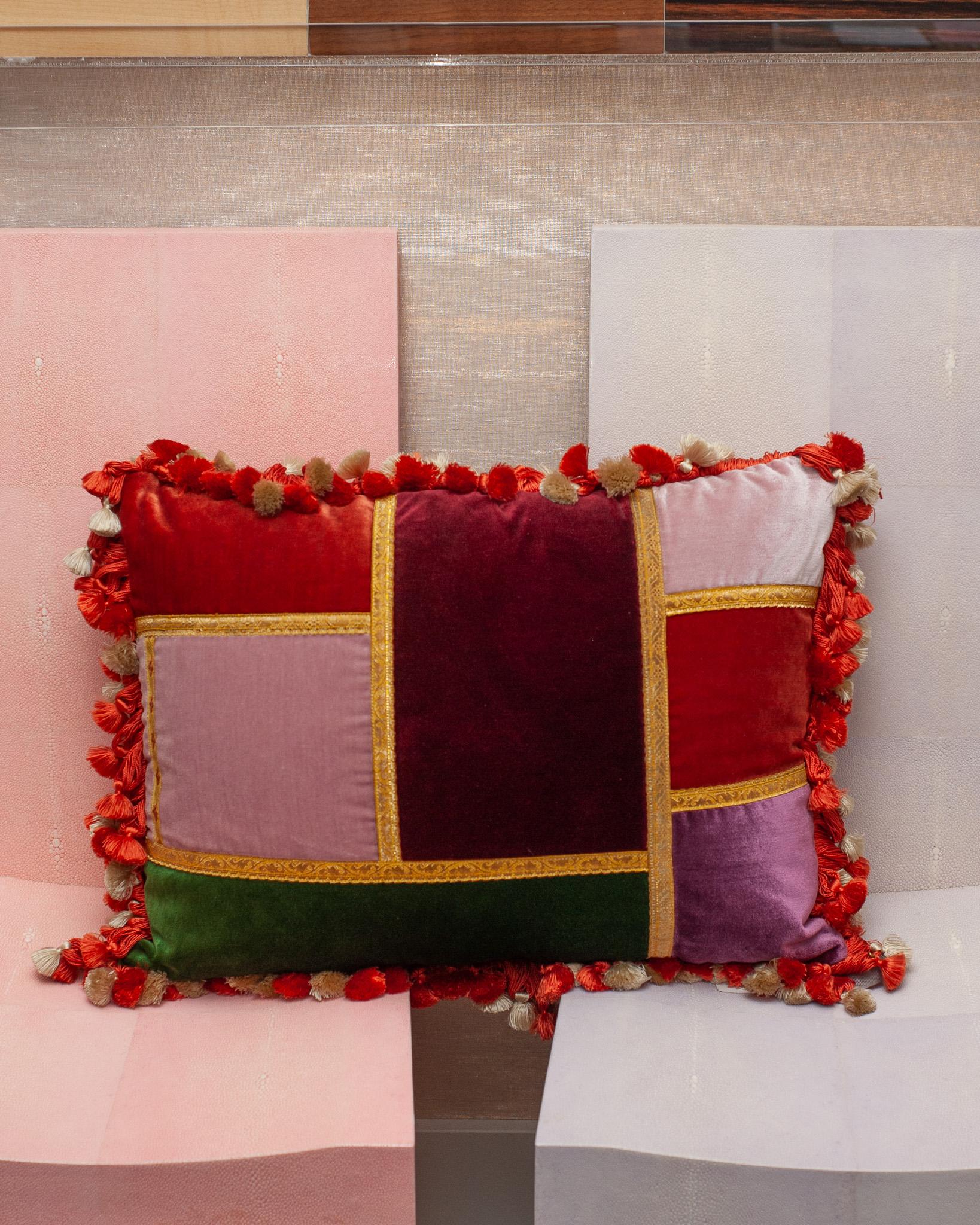 A Studio Maison Nurita patchwork pillow with a variety of luxurious silk and cut pile velvets with vintage metallic gimp and silk tassel fringe trim, backed in red silk velvet and down filled.