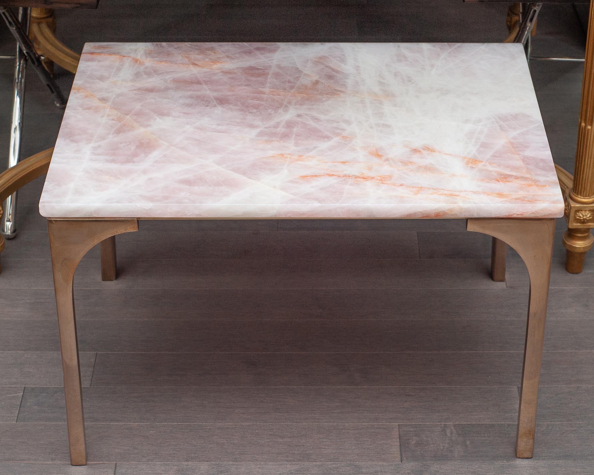A gorgeous Studio Maison Nurita rose quartz and bronze table. Fabricated from a solid slab of the highest quality rose quartz from Brazil, this table features polished rose gold tone solid poured bronze legs. Rose quartz, the stone of universal