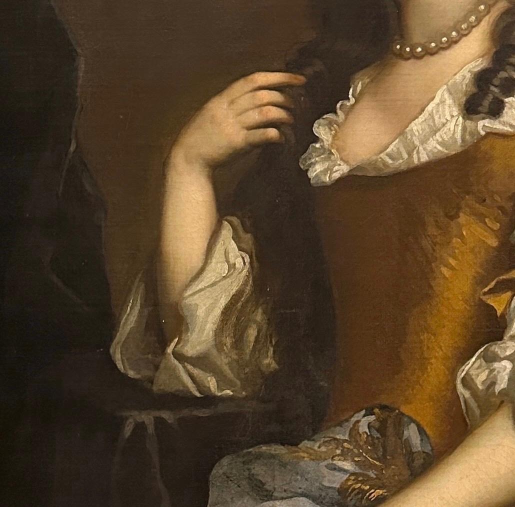 Portrait of a Lady, traditionally believed to be Bridget Bertie (1629-1703/4), the Duchess of Leeds, three quarter length, wearing an amber coloured silk gown, with an embroidered blue mantle, seated in an interior.

Oil on canvas in a 'Lely' panel