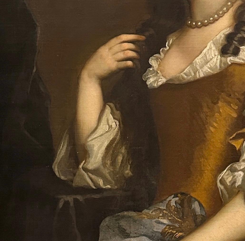 Portrait of a lady, believed to be Henrietta Hyde (née Boyle), Countess of Rochester, (1646-1687) three quarter length, wearing an amber coloured silk gown, with an embroidered blue mantle, seated in an interior.

Oil on canvas in a ‘Lely’ frame