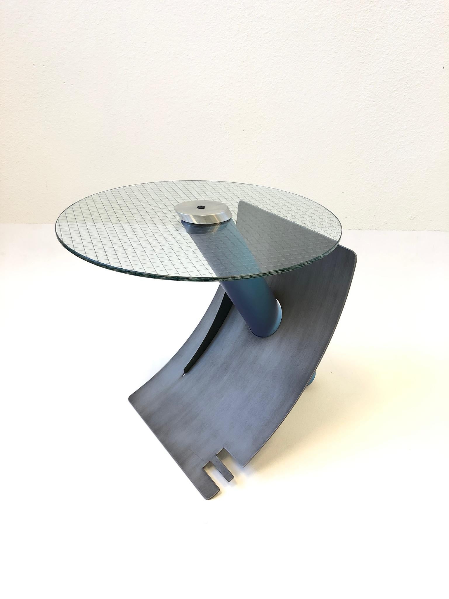 A spectacular studio Postmodern side table by Sculptor Michael Graham. The table is constructed of steel that’s lacquered. The top cap is aluminum that hold the steel grid glass top to the base. The table is signed M. Graham and dated 1994 (see