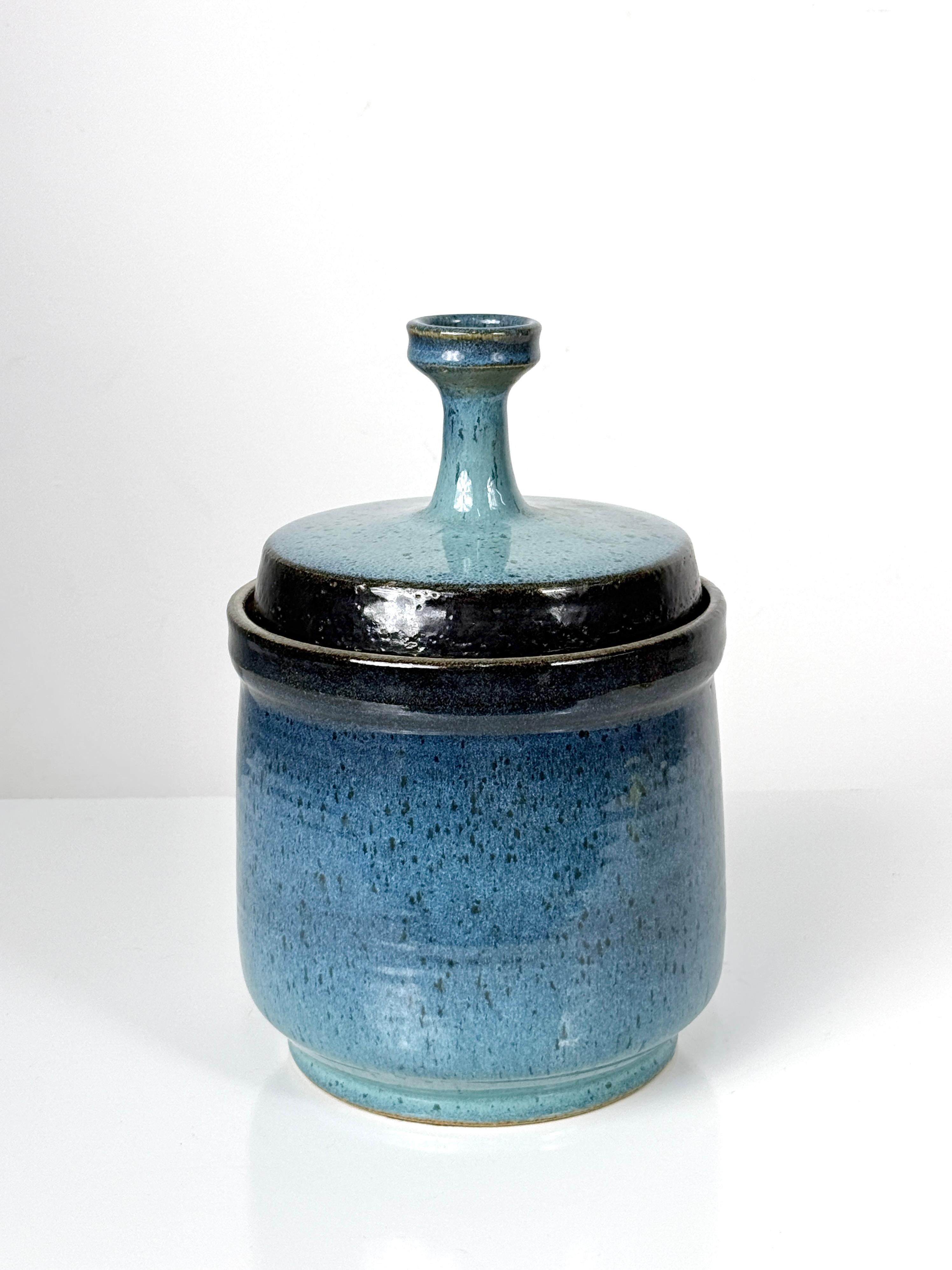 Stupendo vaso in gres smaltato blu del noto artista ceramista del Michigan Gawaine Dart, circa anni '70.

Una bellissima ombreggiatura di smalti blu intenso e turchese con bordo nero a contrasto. 
Etichetta originale apposta sul bordo