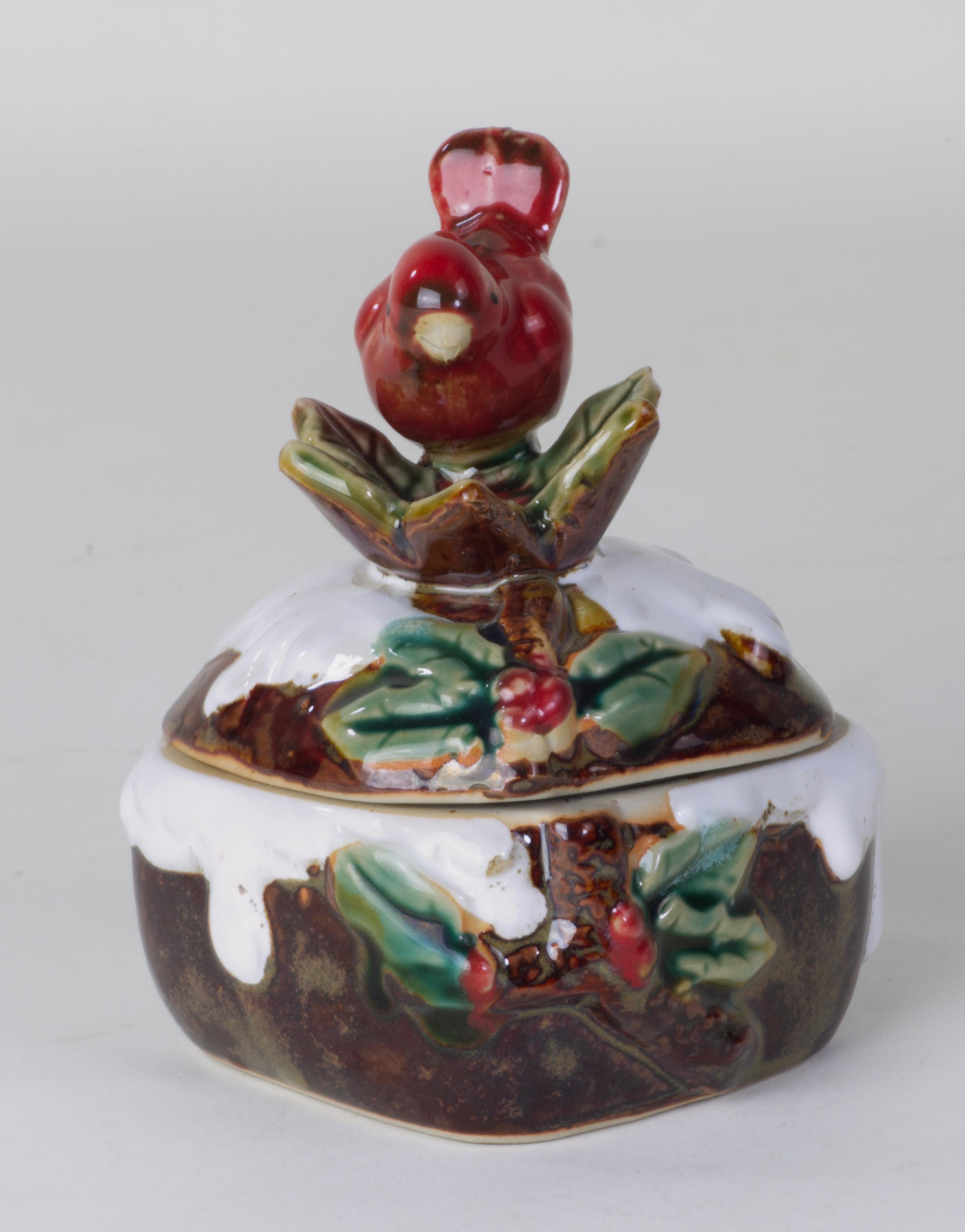 
Studio pottery bowl with lid is decorated with extremely detailed hand formed bird, leaves, and berries. The bird is done in red glaze with brown shading and black eyes; the beak is left unglazed and is shaped to create a realistic portrayal of a