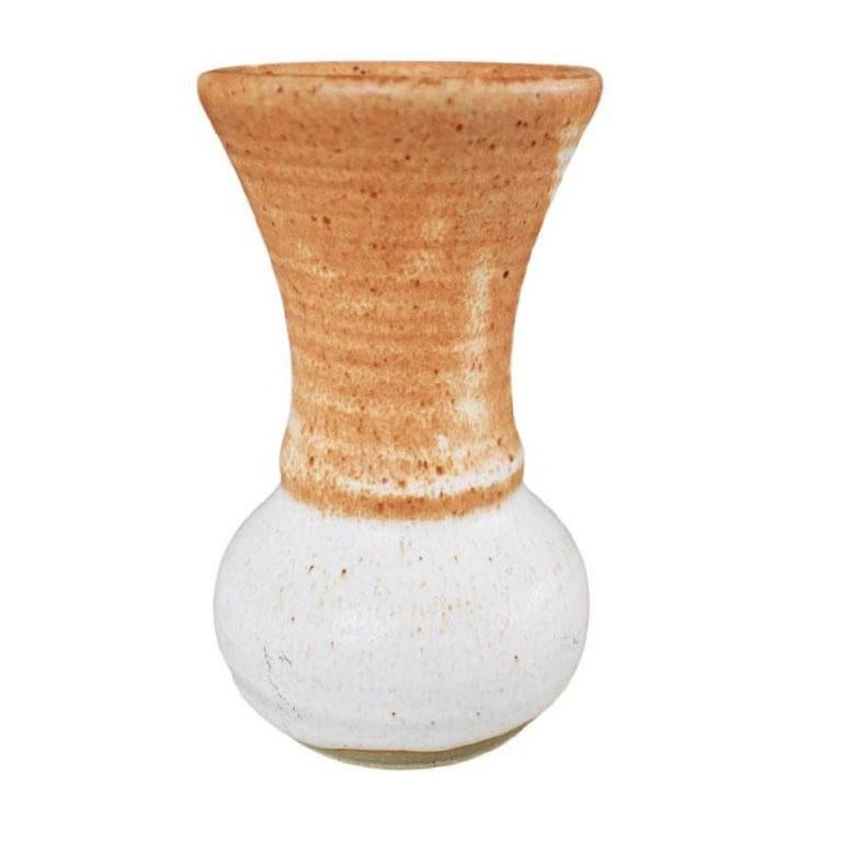 A pretty one-of-a-kind Americana Revival petite ceramic hand-made studio pottery vase. Created from ceramic, this vase reminds of stoneware and is round in form. The top of the piece is fluted and in a dark brown-orange. The bottom is glazed in a