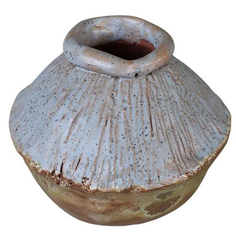 A beautiful piece of studio pottery, this round clay vase will add interest to any space. It is created from clay, and glazed in brown on the bottom, and a light pale lavender on the top. The neck of the vase is capped with a smooth round edge. The