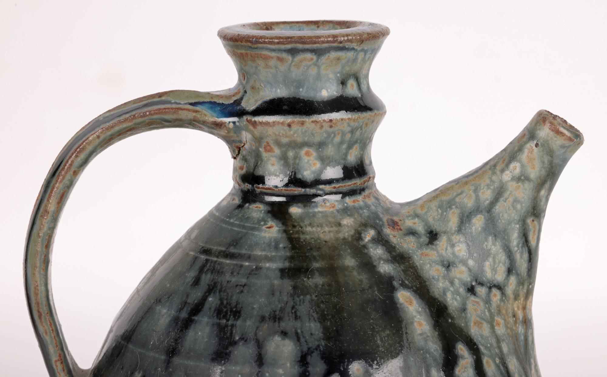 An exceptional and stunning British salt glazed studio pottery flagon decorated in blue streaked glazes dating from the 20th century. This hand thrown stoneware flagon is of tall bulbous shape standing on a flat unglazed base and lower body with a