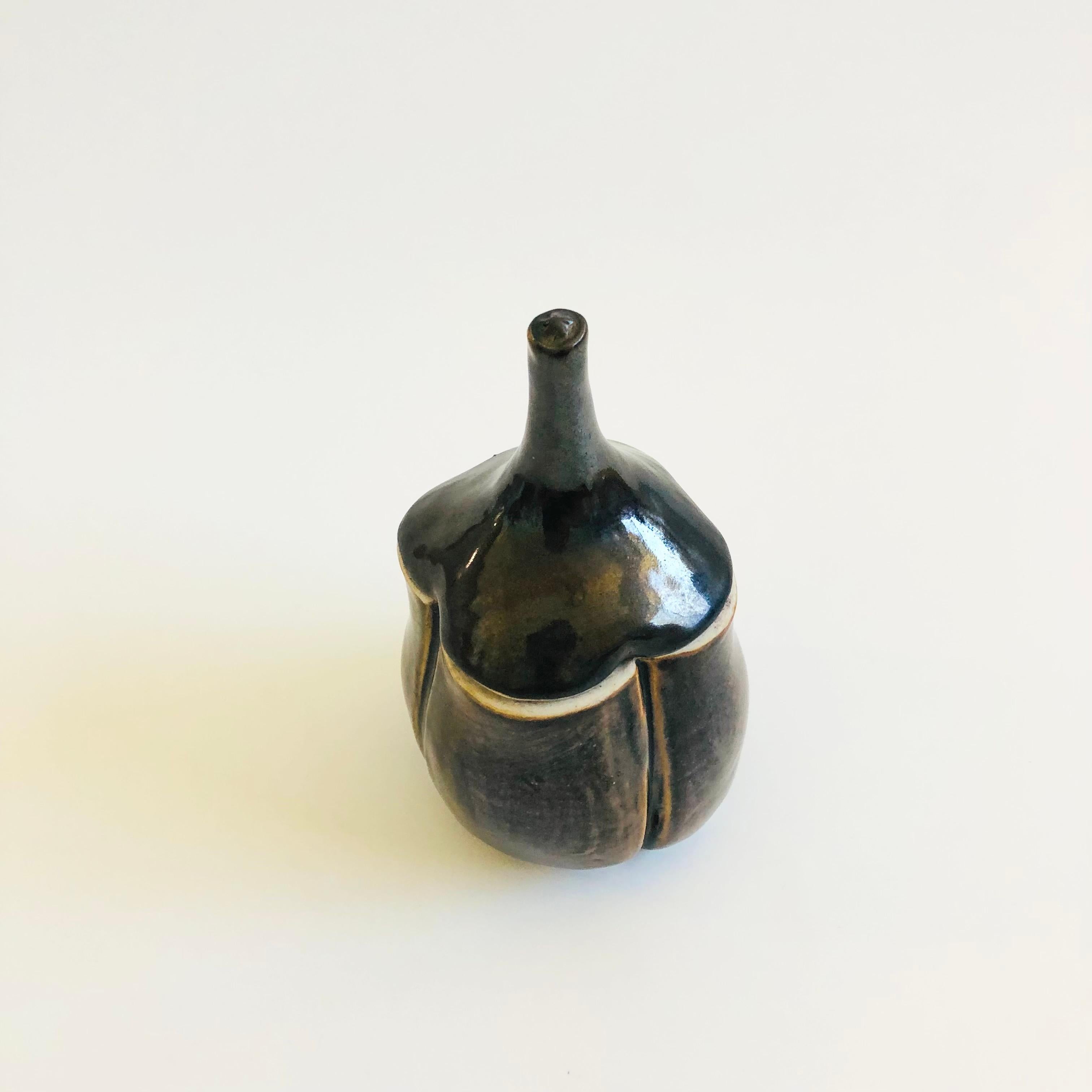 Un barattolo vintage in Studio Pottery a forma di aglio. Rifinito con uno smalto scuro e terroso. Firmato sulla base dal creatore.

