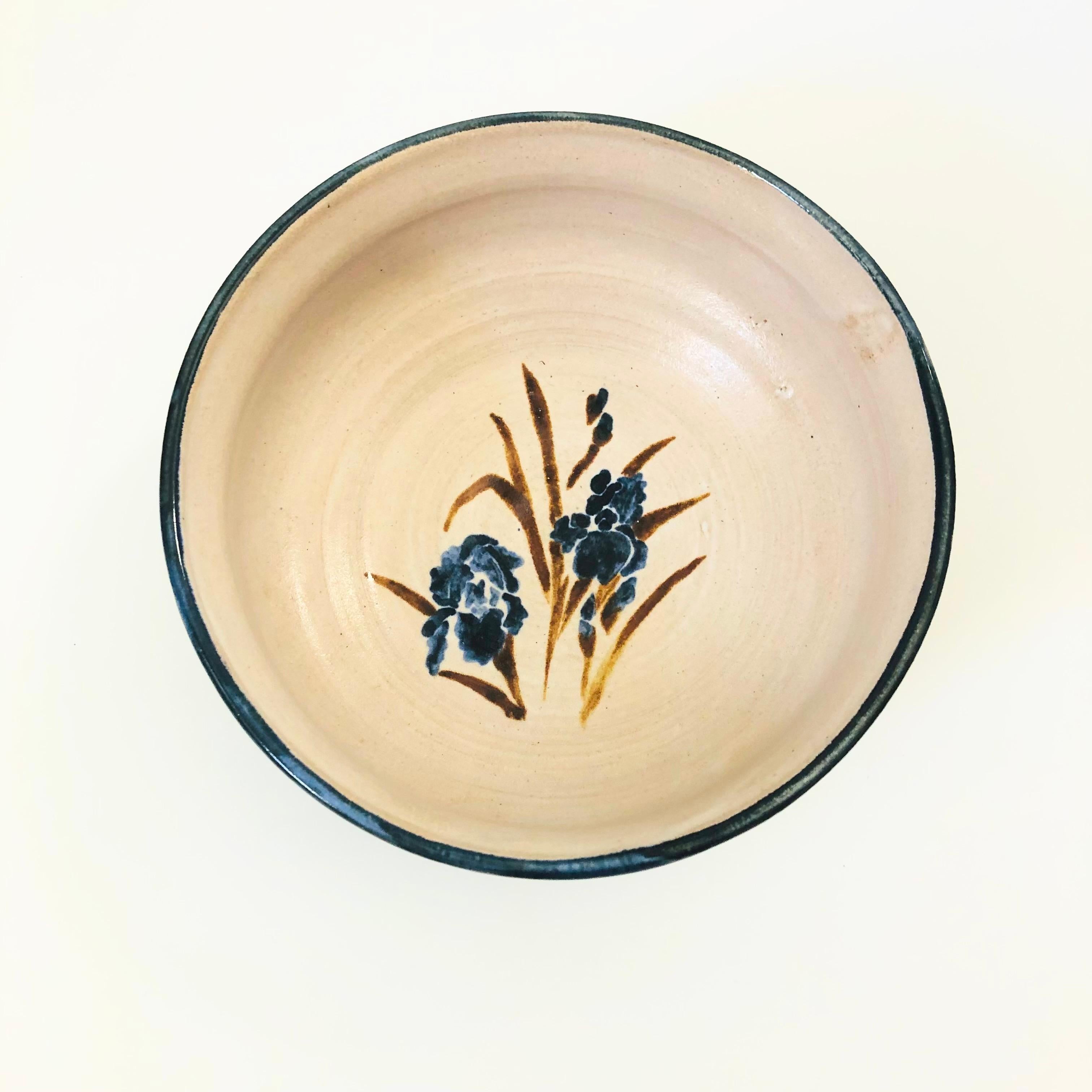 A beautiful vintage studio pottery bowl. Pale purple-gray glaze with a lovely hand painted iris design in the center in blue and brown glazes. Dark blue glaze at the rim. Nice size, perfect for serving a variety of dishes or using as a fruit bowl.