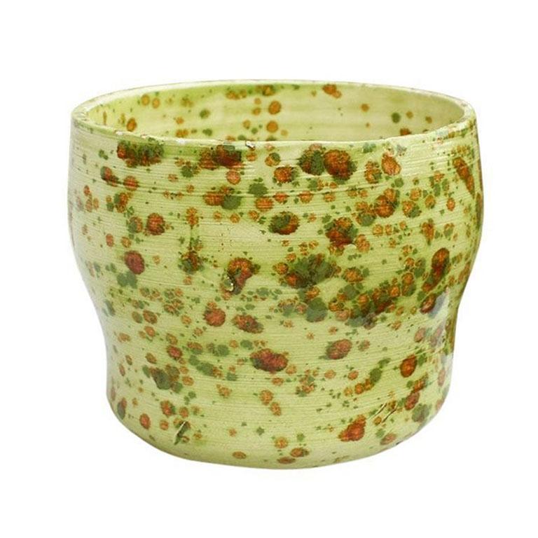 An unusual drip-painted studio pottery bowl or planter. Created from clay in a studio in the 1970s in Oklahoma, this piece is in a bright eye-catching green. It features maroon or red drips throughout. The bottom is signed with the artist's name.