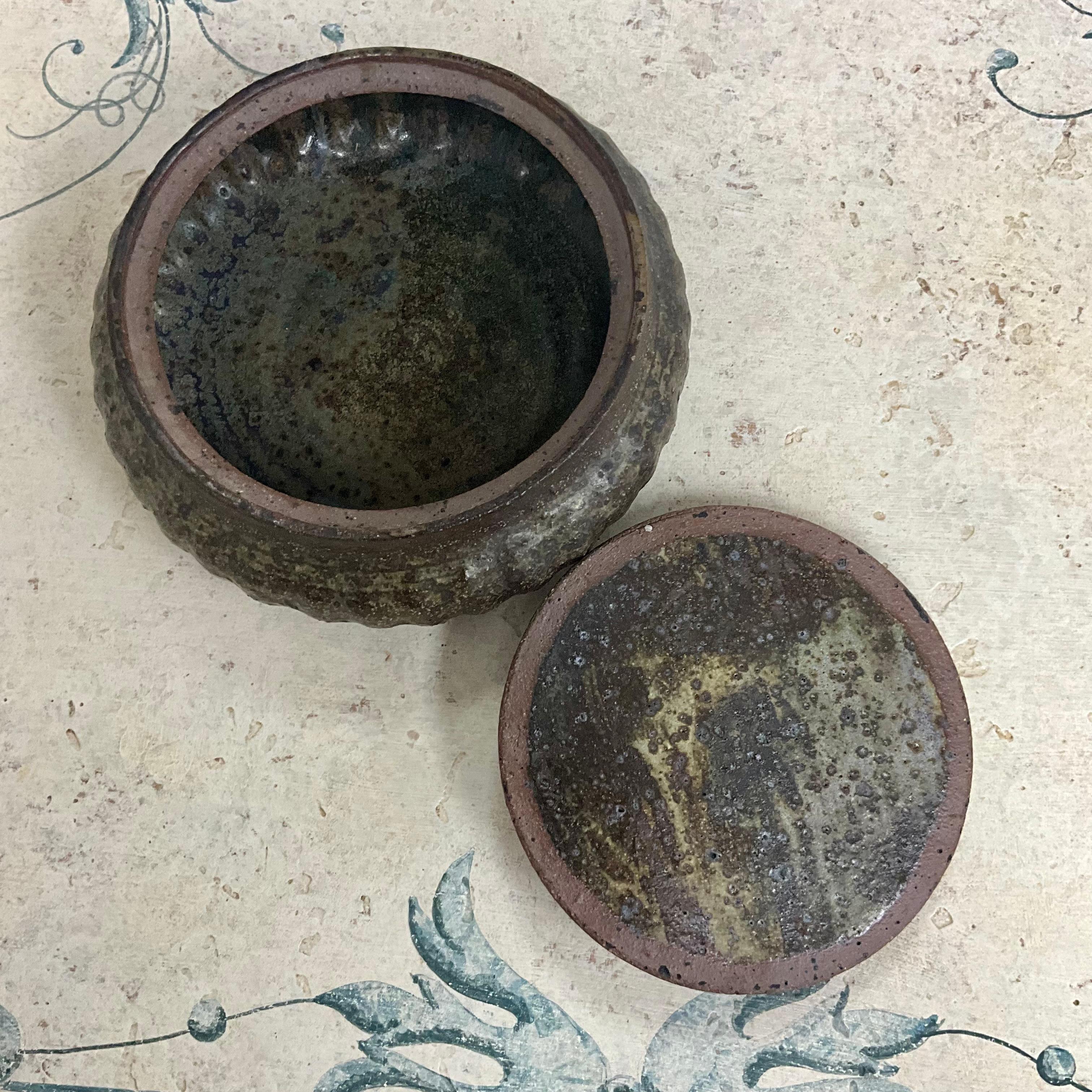 Exceptional lidded hand crafted studio pottery vessel box from the mid 20th century, with organic colors of brown, green and even a light colored plum.  I’m unsure if this piece is signed as it still retains the original green protective felt on the