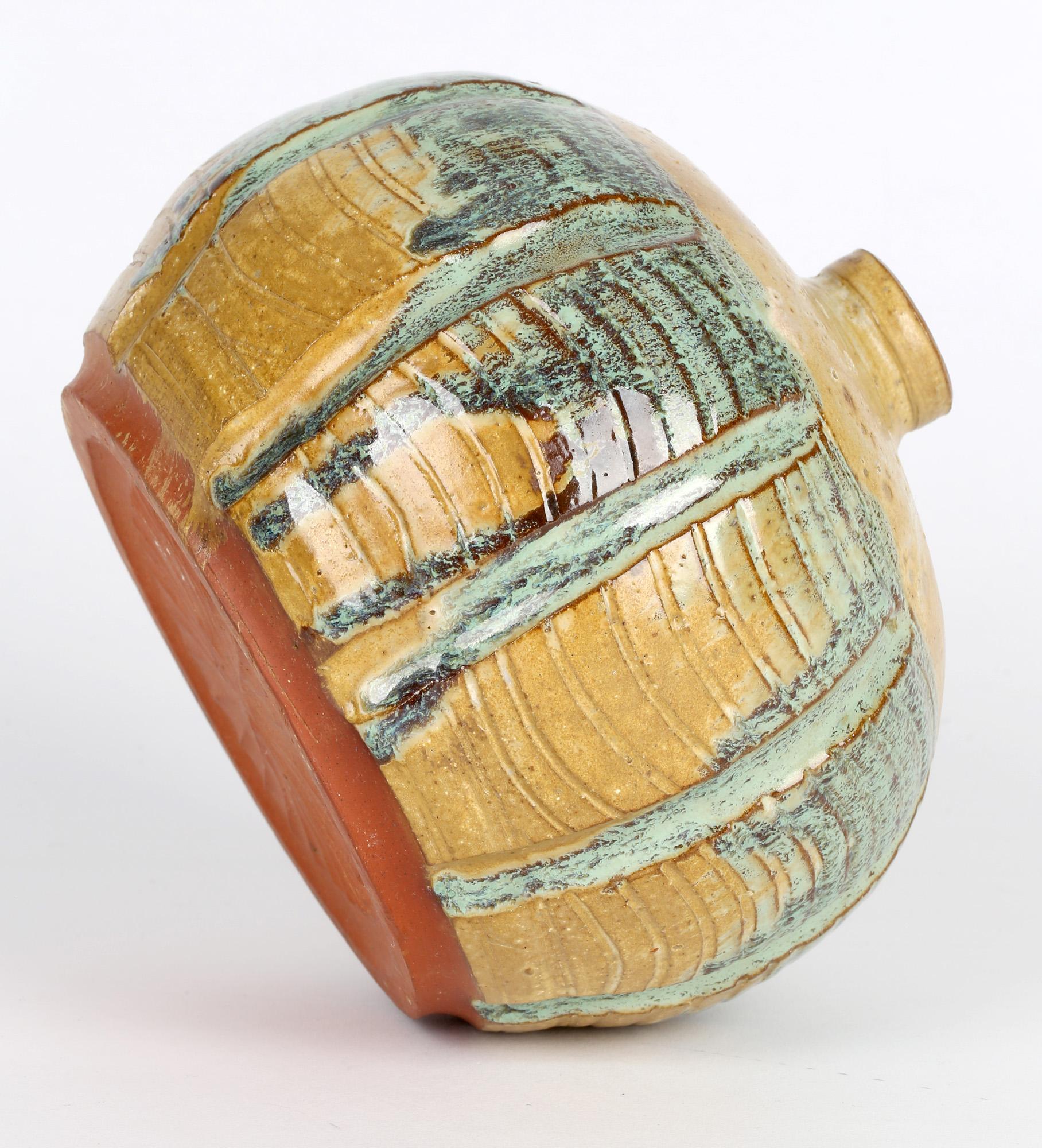 Stylish studio pottery vase decorated in volcanic mustard and green streaked glazes signed JL to the base and dated 1979. The vase made in red terracotta clay is of squat rounded shape with vertical and horizontal ribbed patterning and with a small