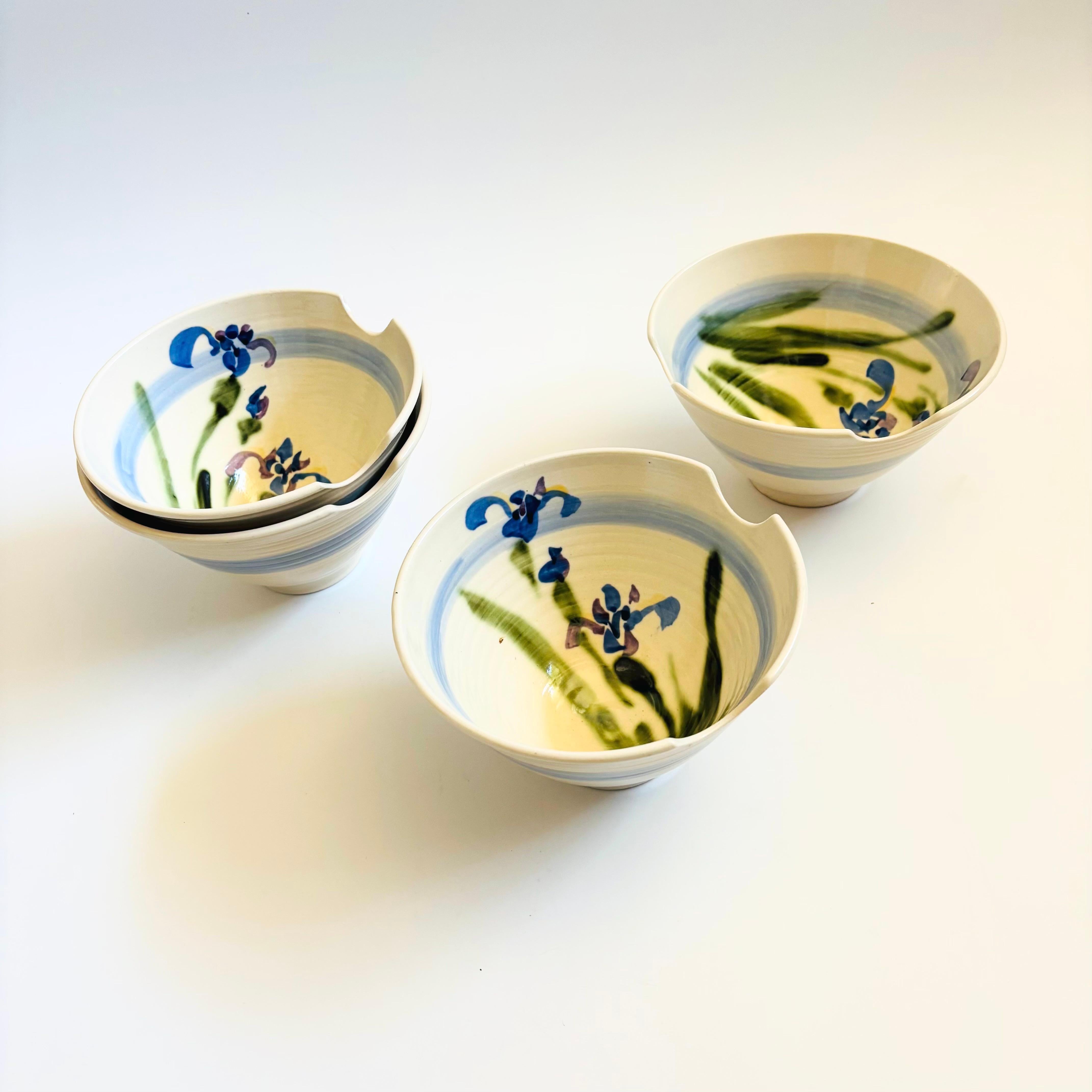 Un ensemble de 4 bols à nouilles vintage en poterie de studio. Chacun d'entre eux possède deux rainures formées dans les bords pour accueillir des baguettes. Jolis motifs d'iris peints à la main à l'intérieur des bols. Chacune est signée sur la