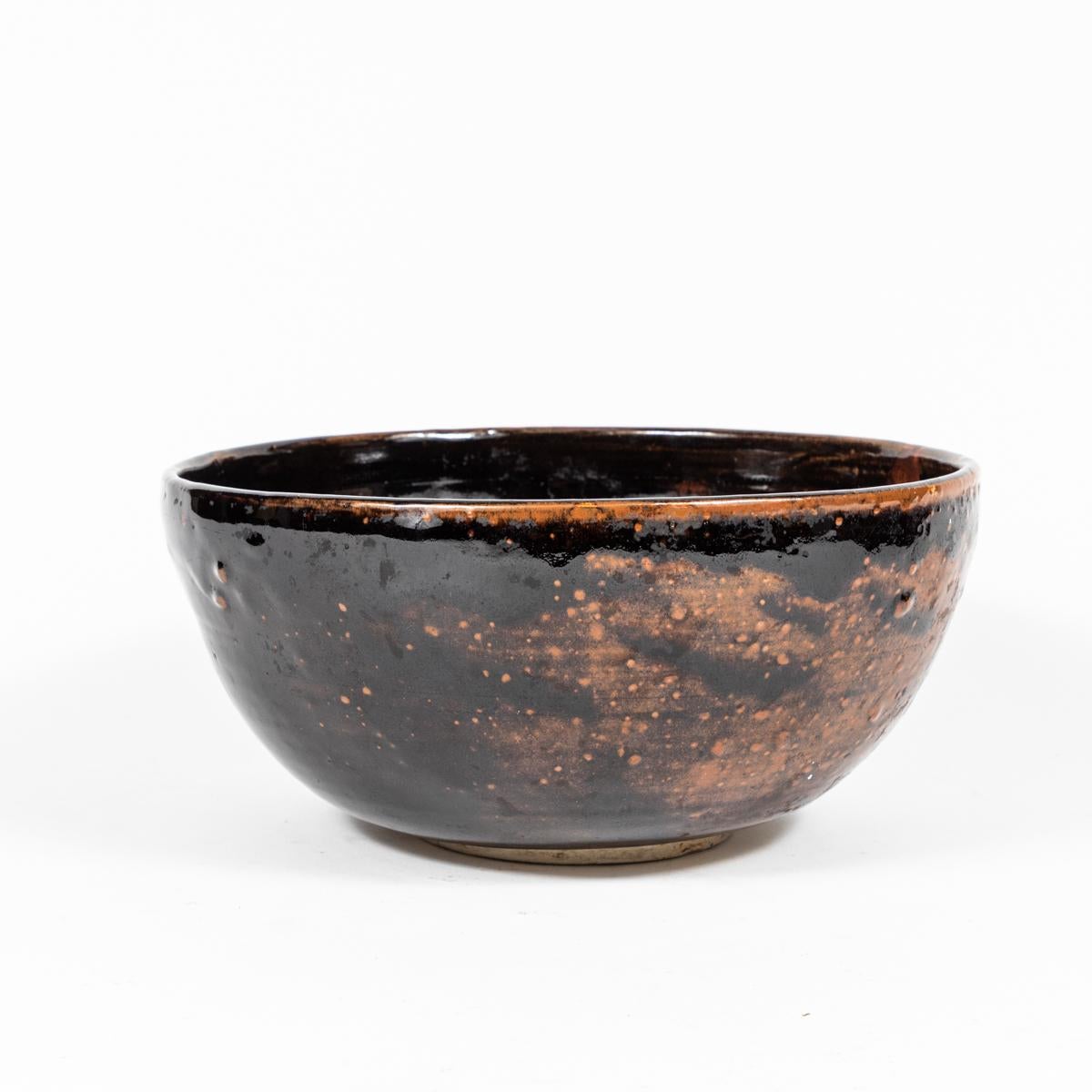 English mid-century studio pottery bowl. Notable for its unique glazing pattern of deep inky browns and rusty golden neutrals, the semi-smeared drip pattern that has formed on both its interior and exterior has a flowing and relaxed, wabi-sabi