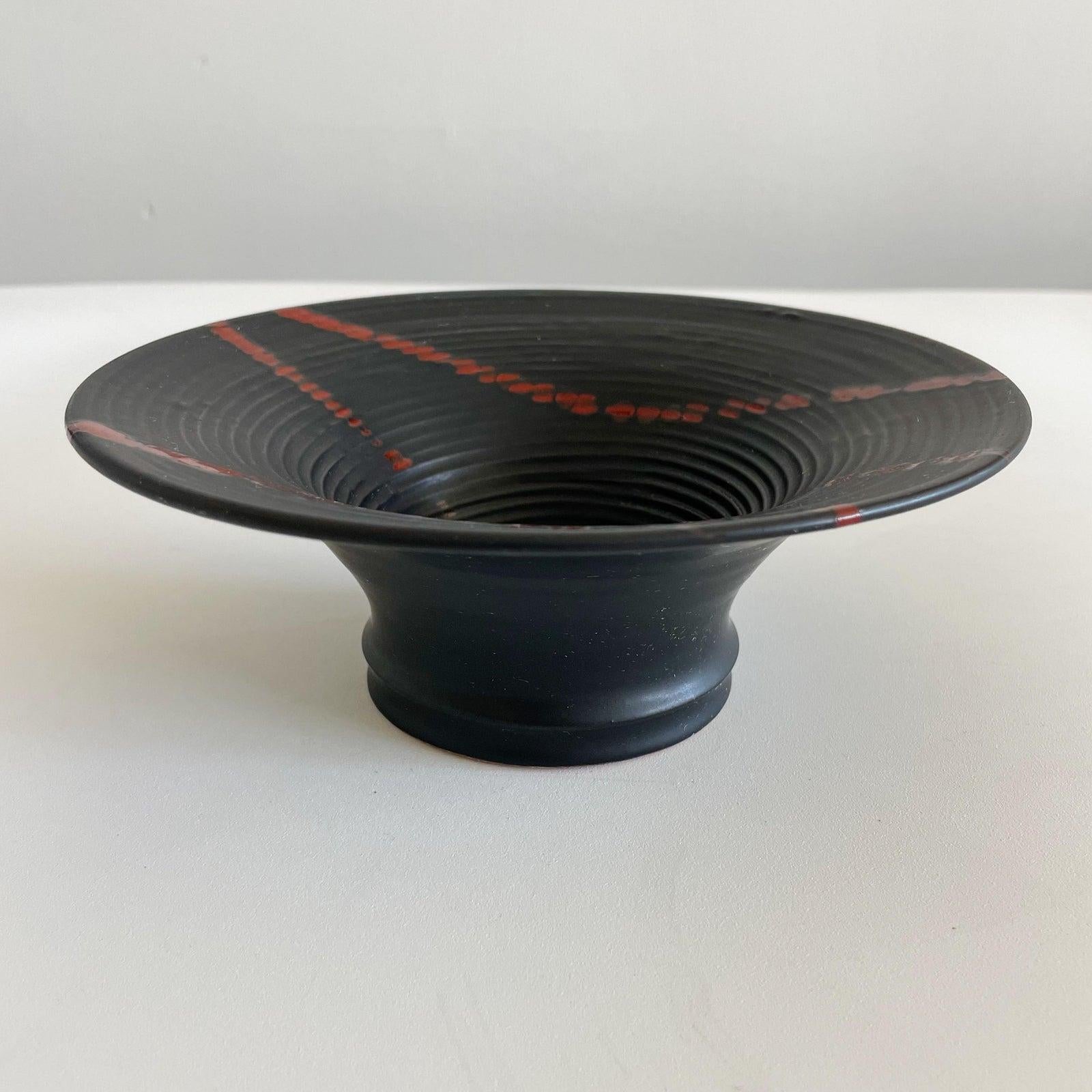 Studio Pottery small large rimmed bowl in black with red decoration. Signed on underside with illegible signature.