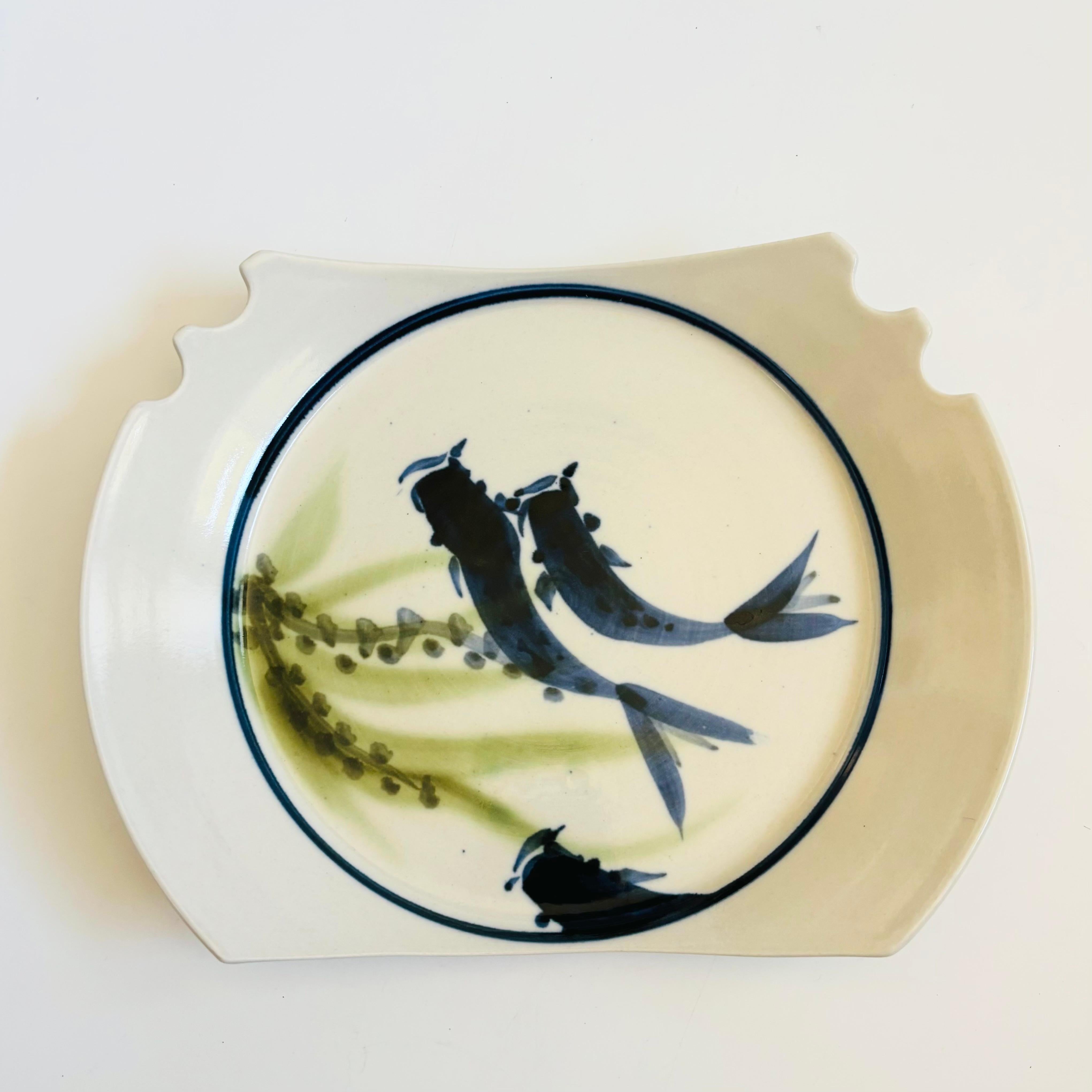 A vintage studio pottery serving plate with a lovely hand painted fish design. Grooves have been formed on one side for holding chopsticks. A wonderful and unique serving piece. Signed on the base.

