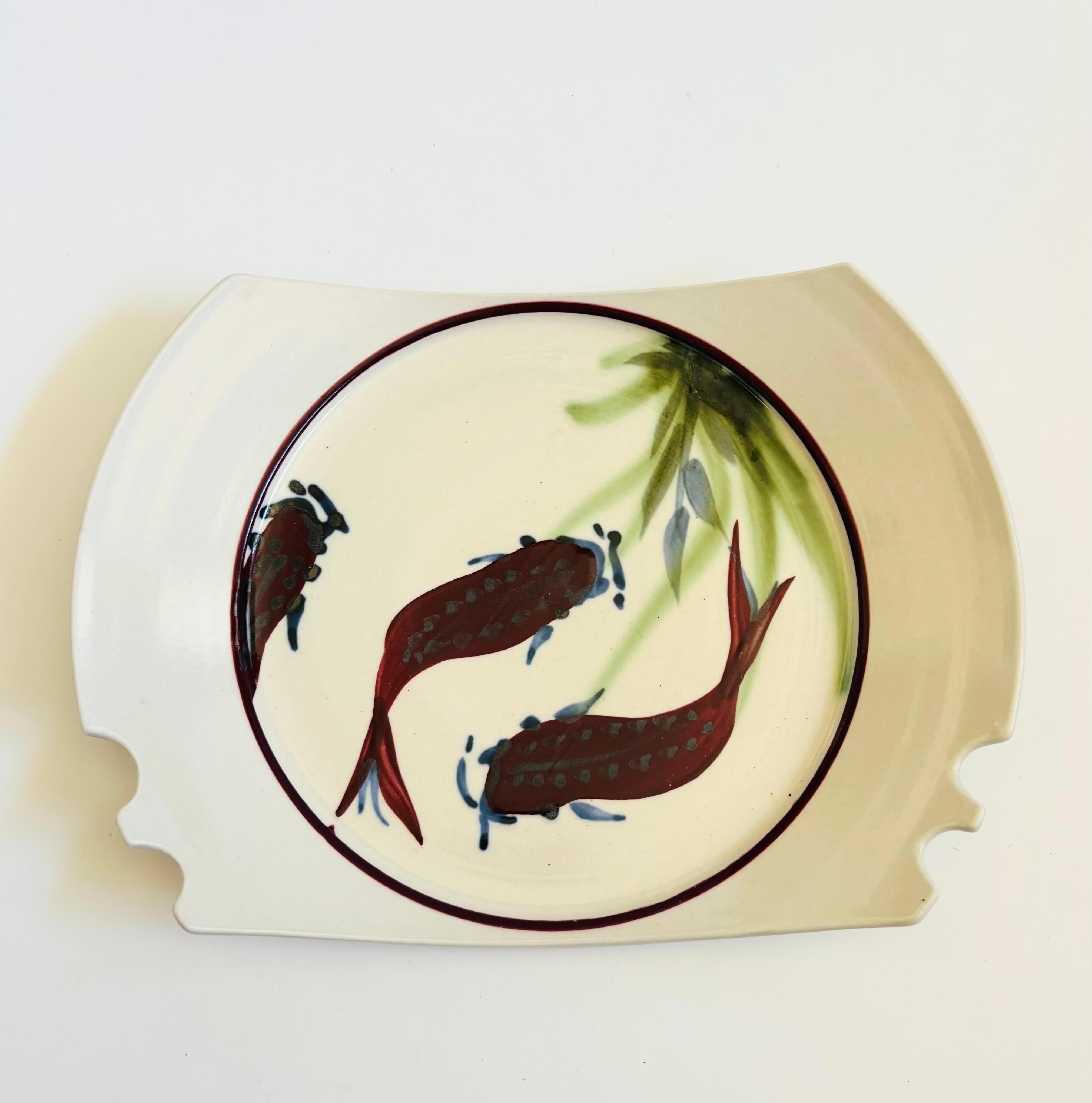 A vintage studio pottery serving plate with a lovely hand painted fish design. Grooves have been formed on one side for holding chopsticks. A wonderful and unique serving piece. Signed on the base.

