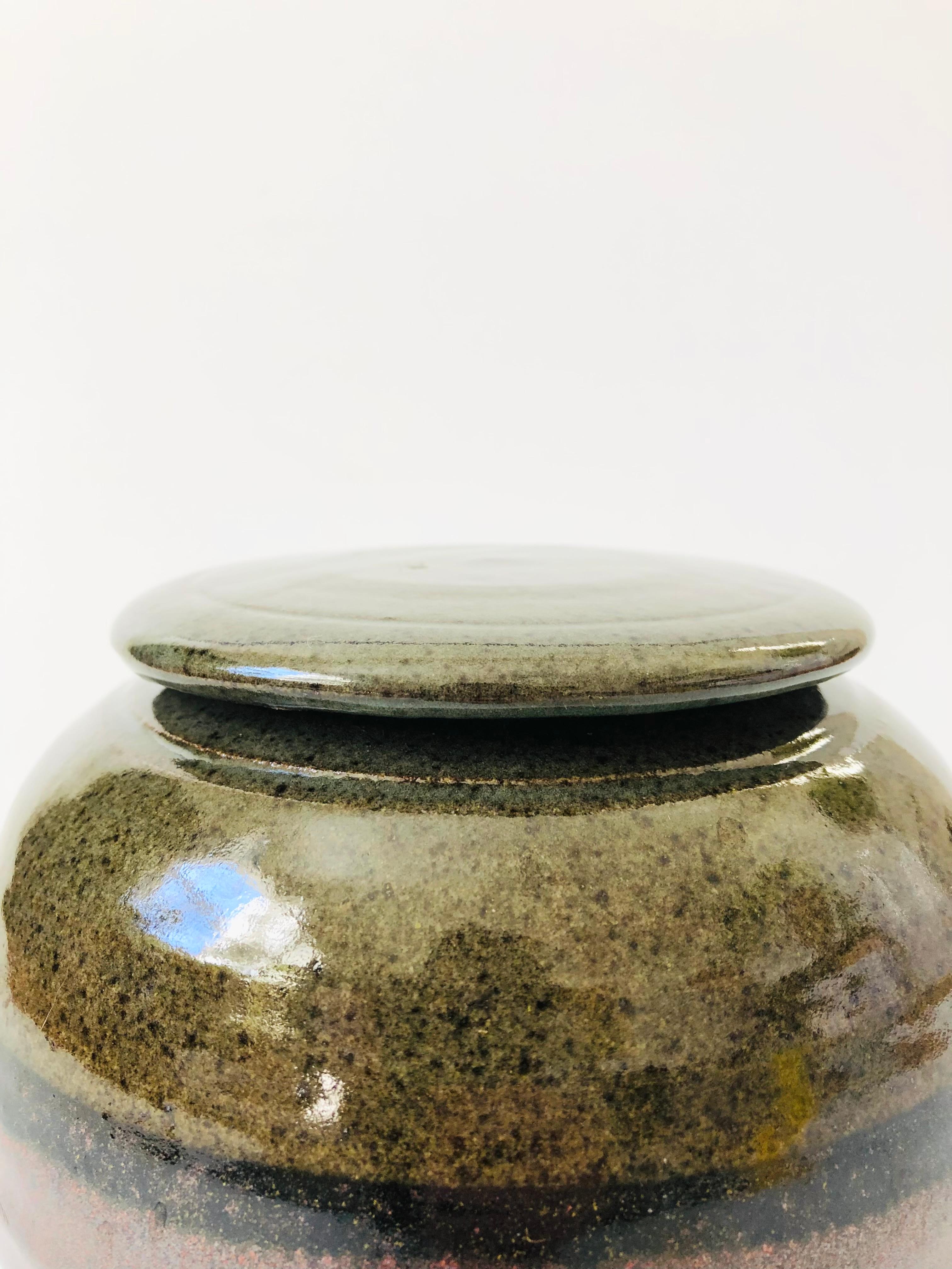 Ein handgefertigter Studio-Keramik-Deckelbehälter im Vintage-Stil. Ausgeführt in zwei erdfarbenen Glasuren. Schöne Kugelform in einer vielseitigen mittleren Größe, perfekt für die Aufbewahrung in der Küche. Signiert auf dem Sockel.

