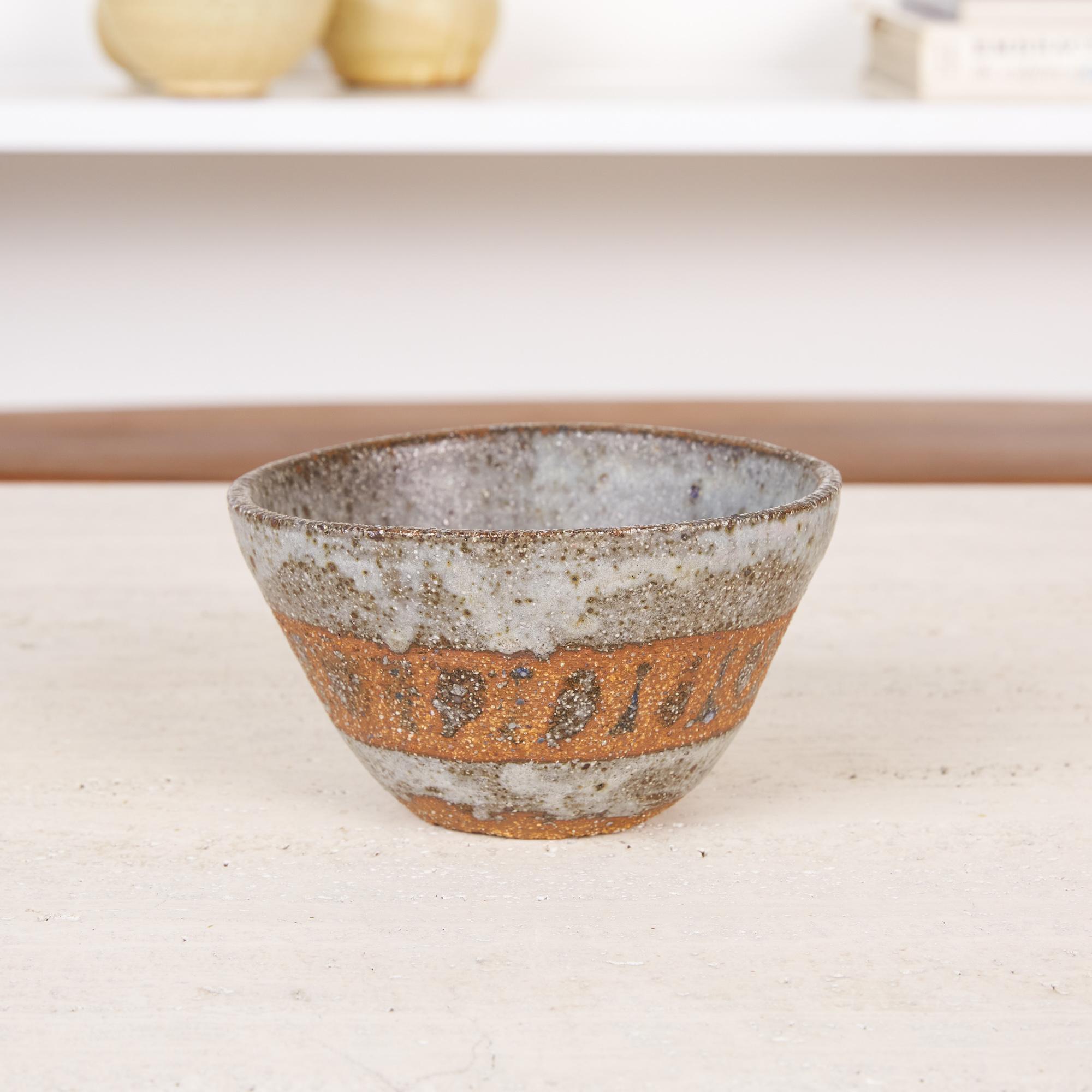 Studio pottery stoneware bowl. This small bowl is made from a red stoneware clay and features a striated icy gray glaze exterior accented by a band of unglazed clay detailing around the bowls diameter. The base of the interior of the bowl is