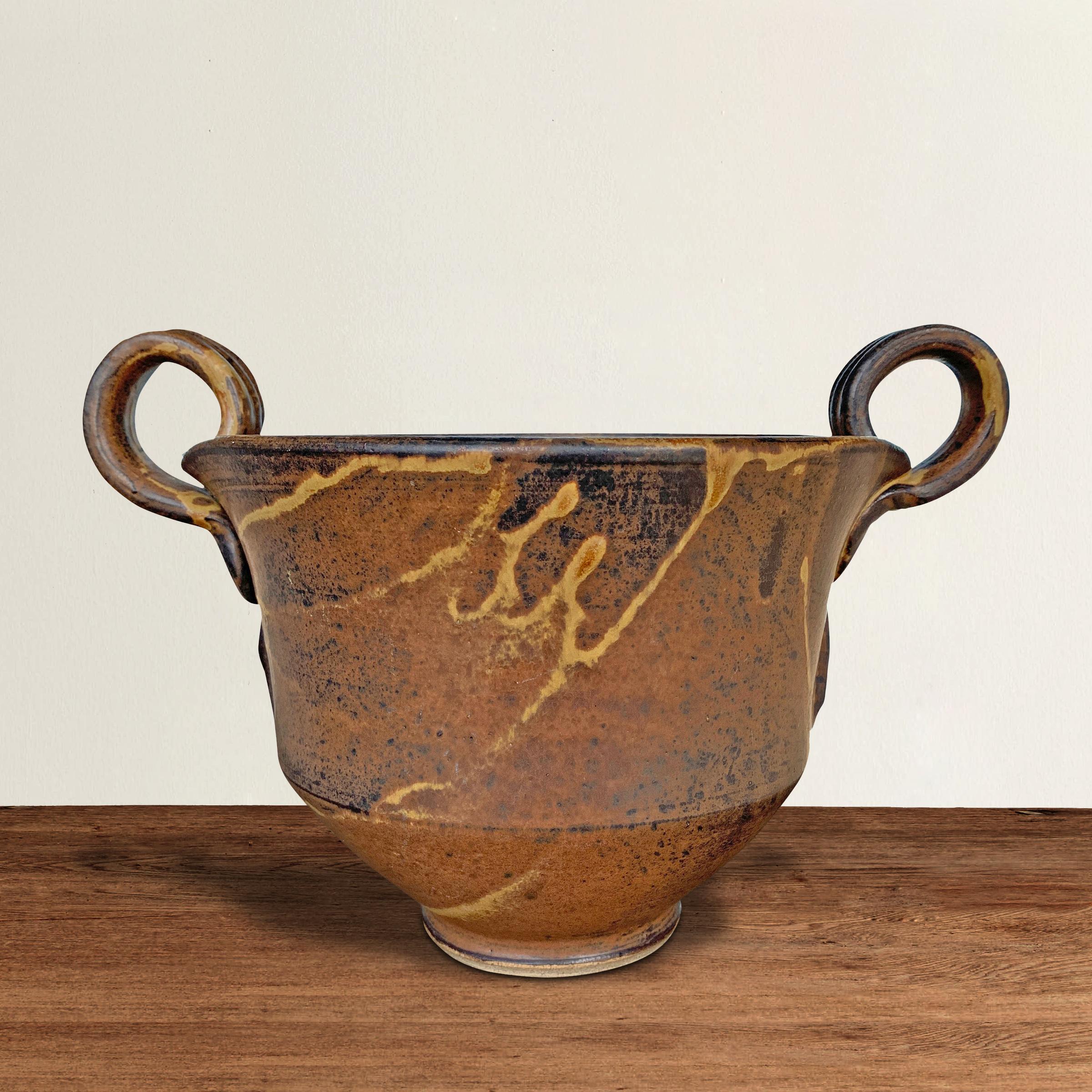 An über chic mid-20th century American studio pottery ceramic urn with a Grecian form containing two round handles applied to vessel with a wide rim and narrow foot. Perfect just as it is, but it can also hold your favorite flowering plant, or fill