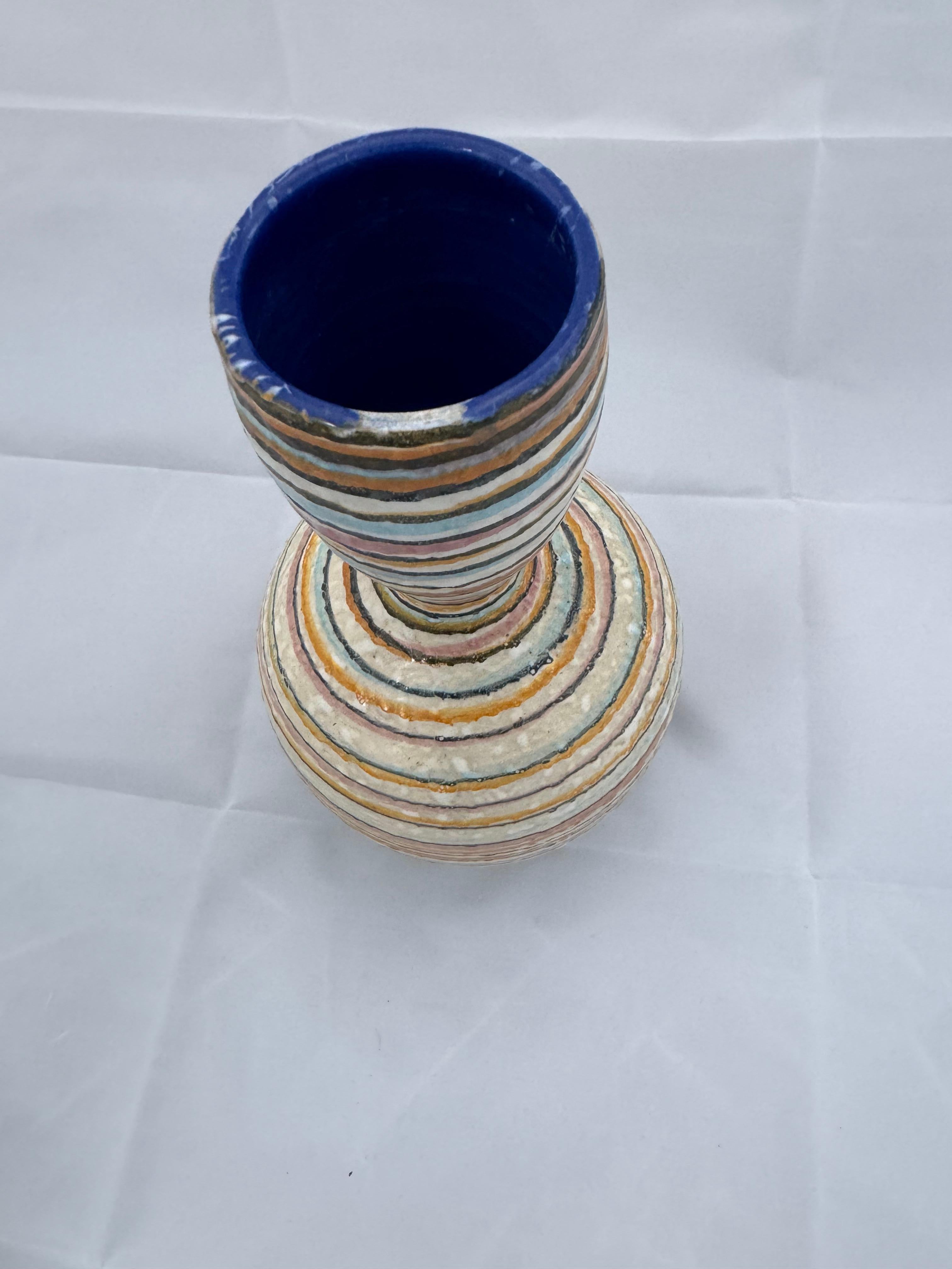 Hand made studio pottery vase with colorful blue, yellow, white black, brown and orange stripes. Reminiscent of Fantoni pottery, this piece is a real eye catcher. The rim shows a slight divot which is actually in the glazing and not a chip. A