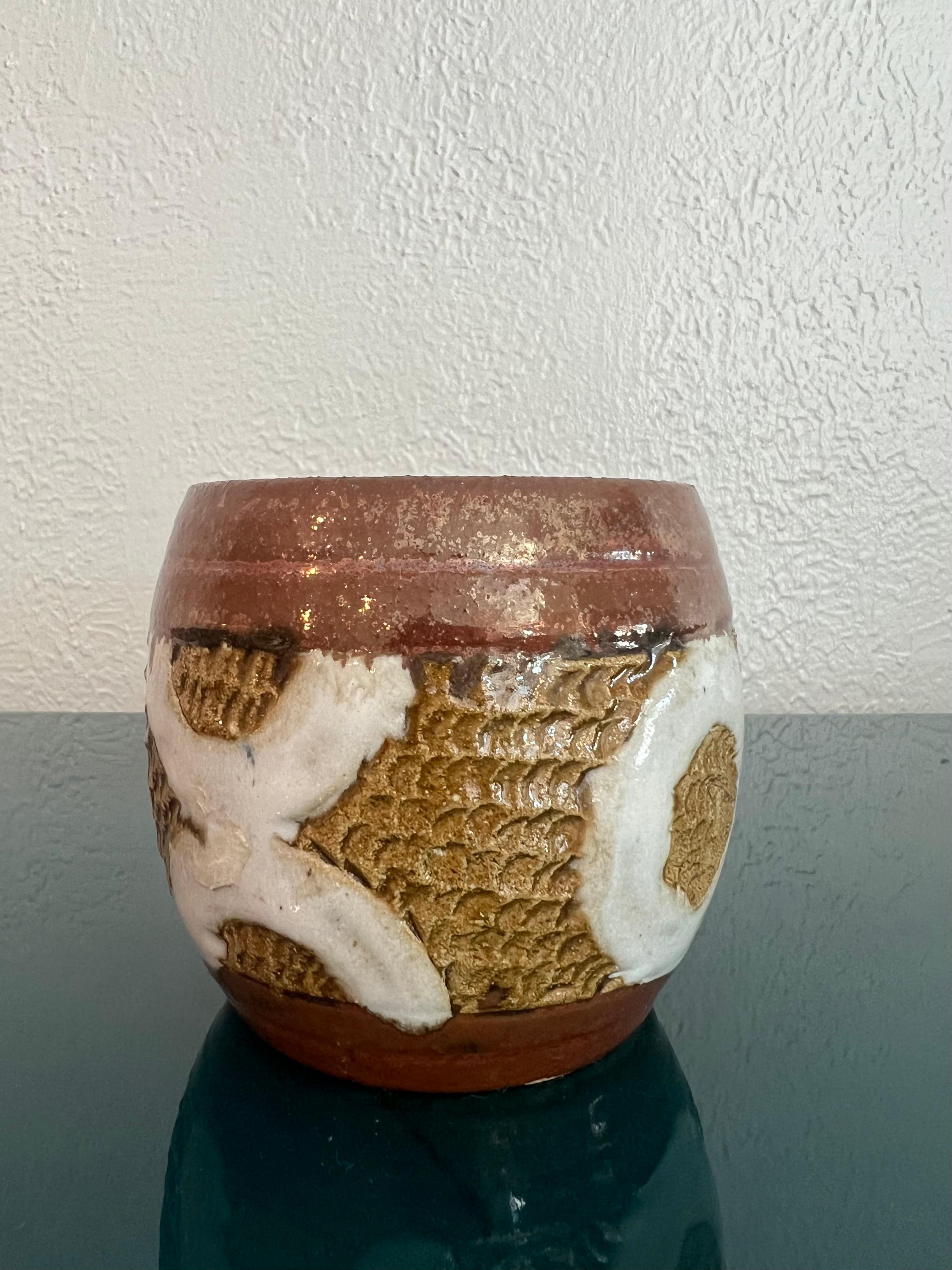 Studio pottery vessel. Nice glaze work with XO motif.

Would work well in a variety of interiors such as modern, mid century modern, Hollywood regency, etc. Piece blends seamlessly with other designers such as Warren Platner, Paul Evans, Gabriella