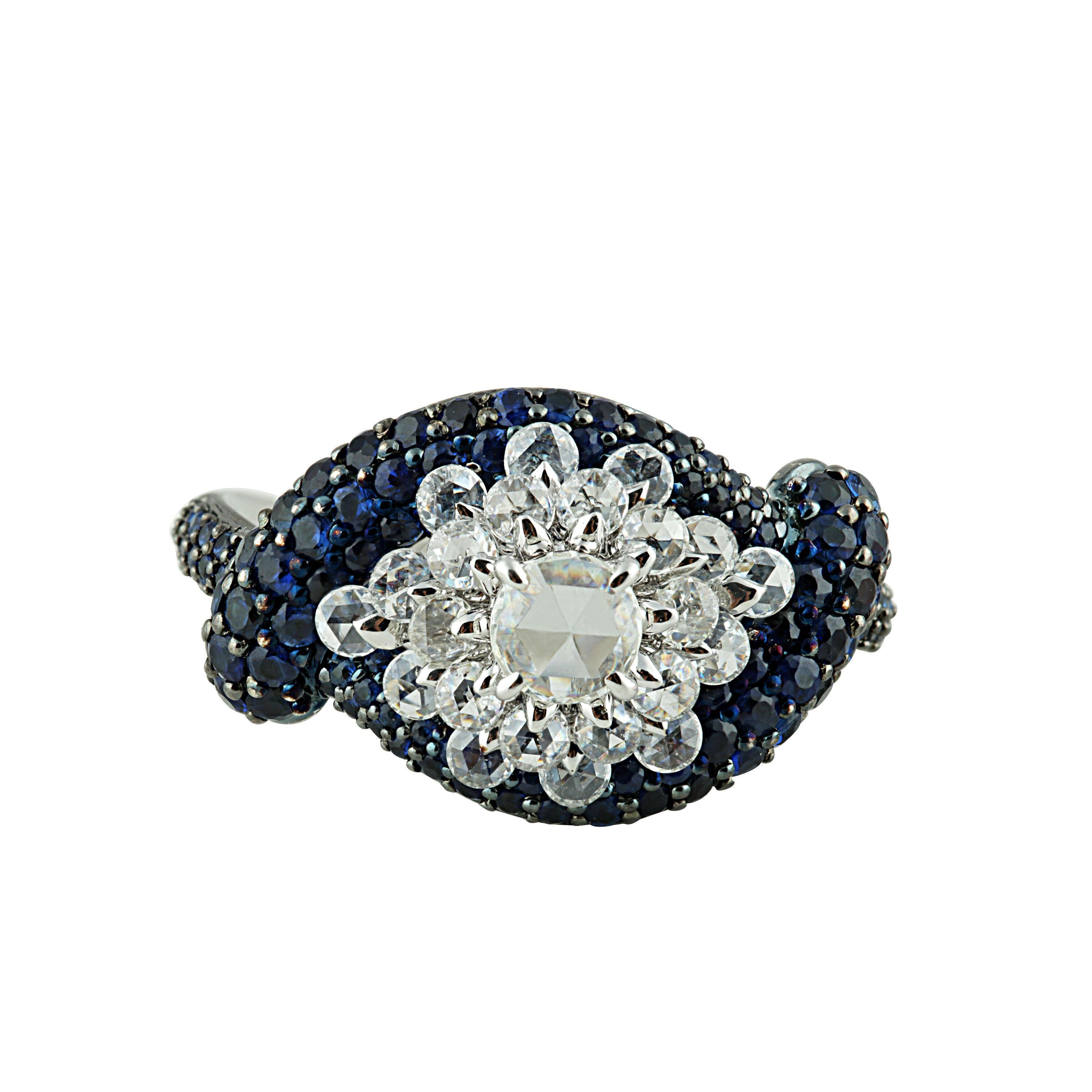 Blue sapphire and rose cut diamond ring

A cluster of round rosecut diamonds is enhanced by and encased within a regal row of blue sapphires, giving this 18K white gold ring a look and feel like no other. Set in prong, pave and drill settings using