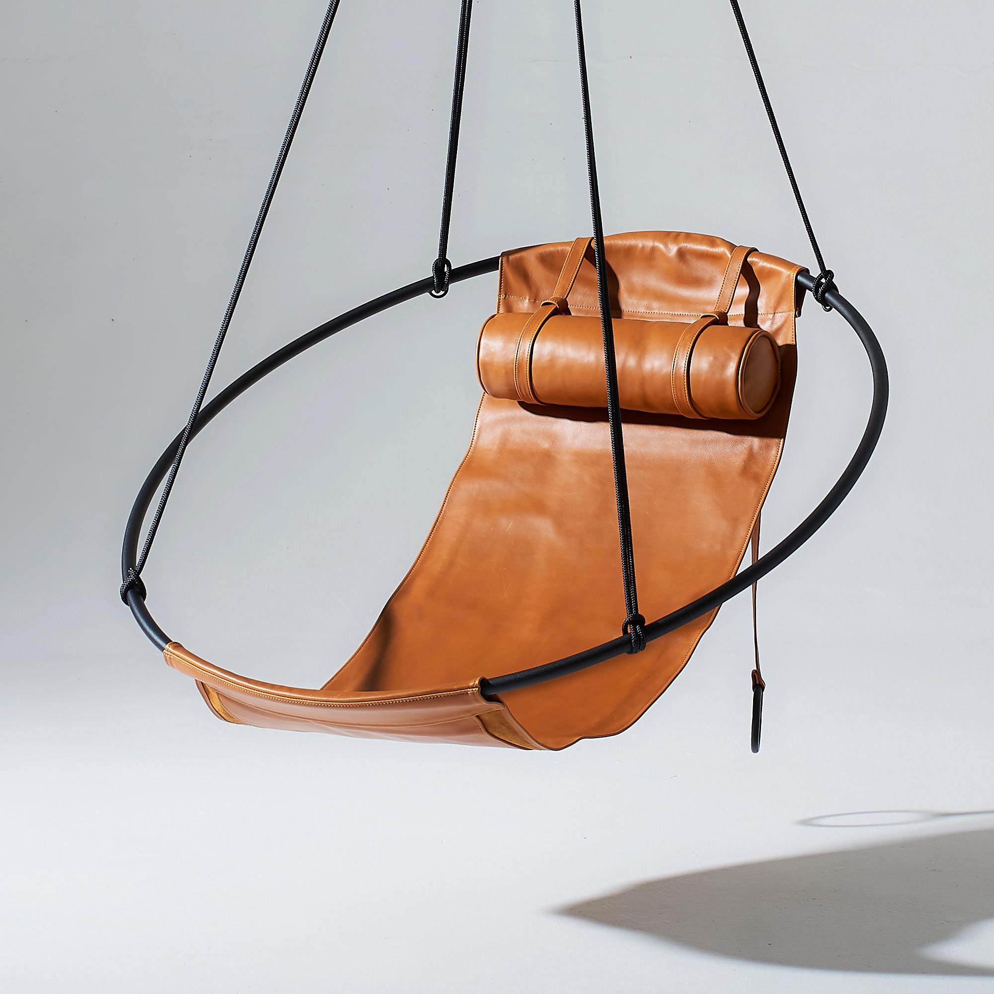 Dépouillé de tout excès, ce fauteuil suspendu présente un cadre circulaire dans lequel pendent des feuilles de cuir souple, pour créer une expérience élégante, sexy et très confortable. Les lignes épurées et la légèreté de cette chaise lui