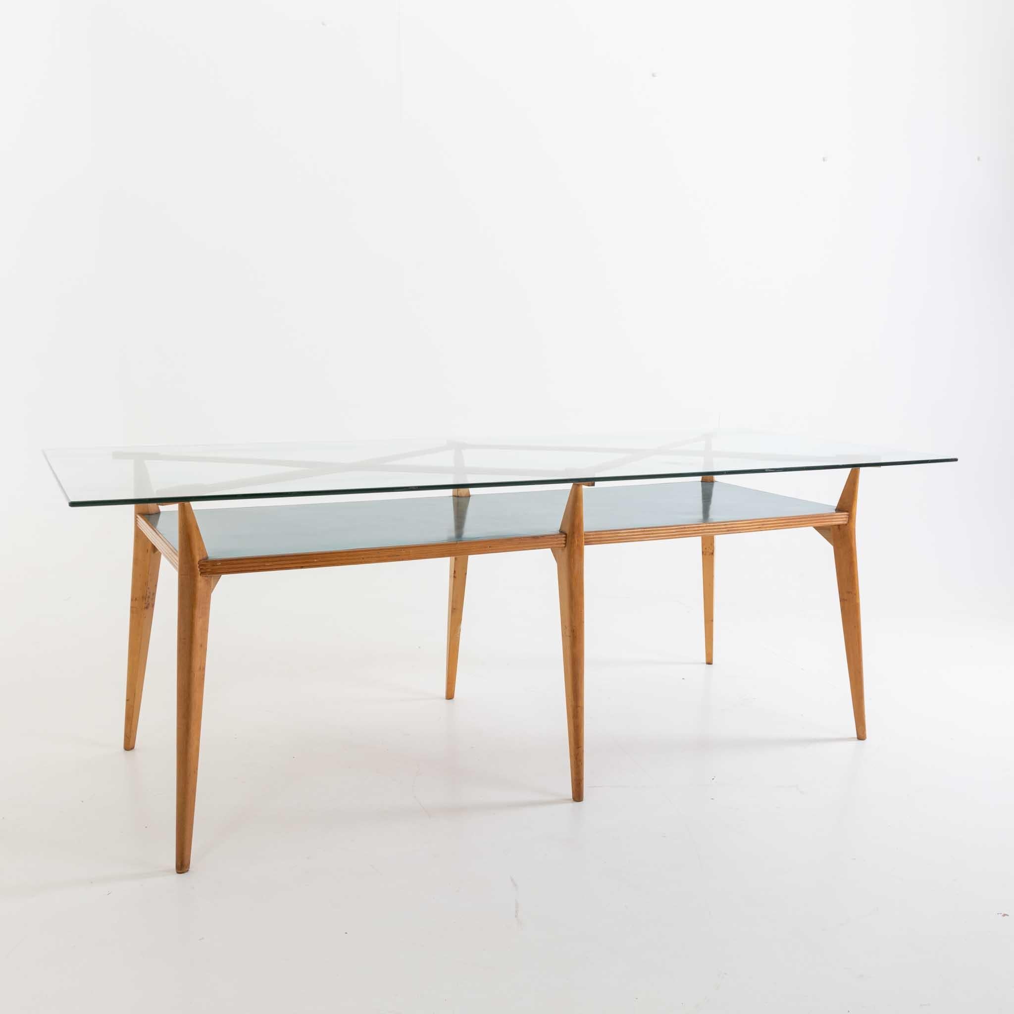 Auf sechs konischen Beinen stehender Tisch mit Glasplatte und rautenförmigen Verstrebungen über der blau laminierten Tischplatte. Der Tisch wurde in der Mitte des 20. Jahrhunderts für ein Studio des Architekten Vittorio Armellini entworfen. Die