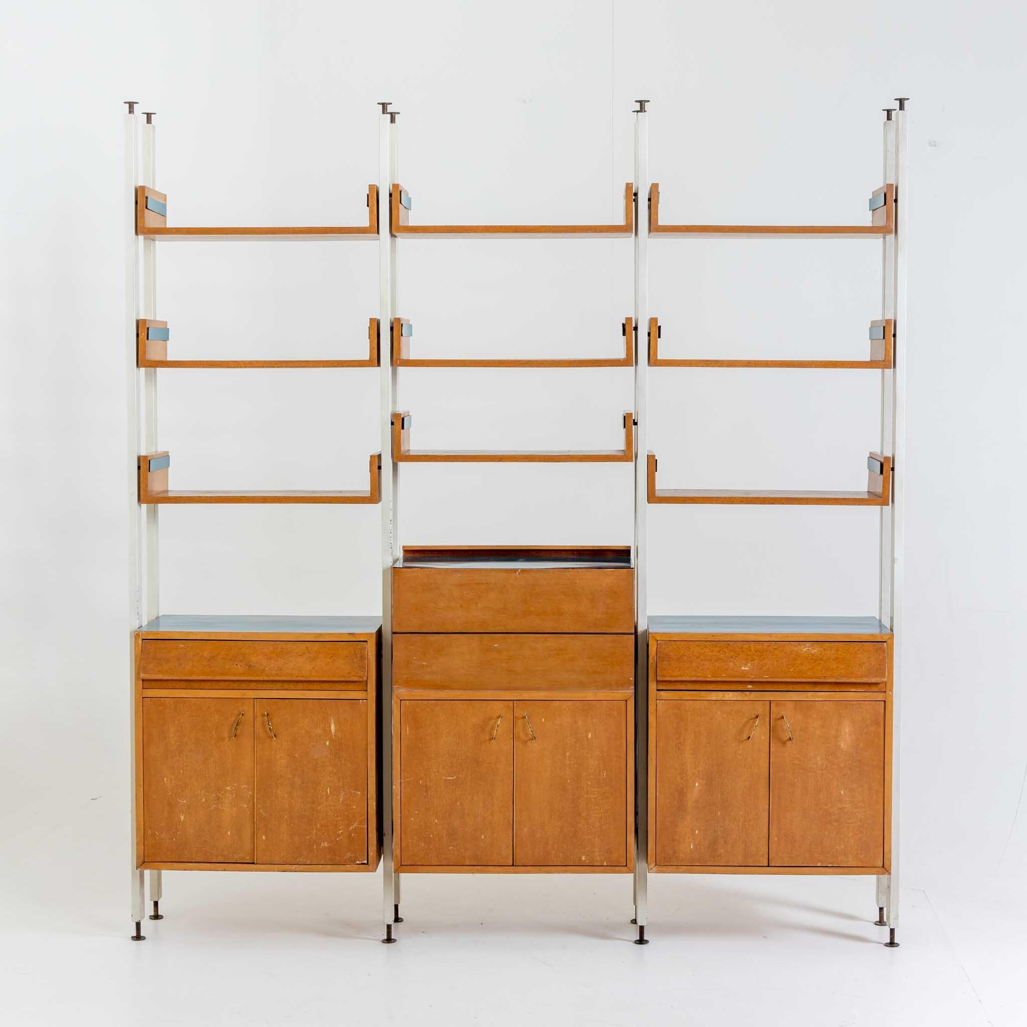 Large three-piece wall unit with bar element in the middle and two-door lower cabinets and three shelves each. The wall unit is veneered in maple with light blue finishes. The wall unit was designed in the mid-20th century for a studio by architect