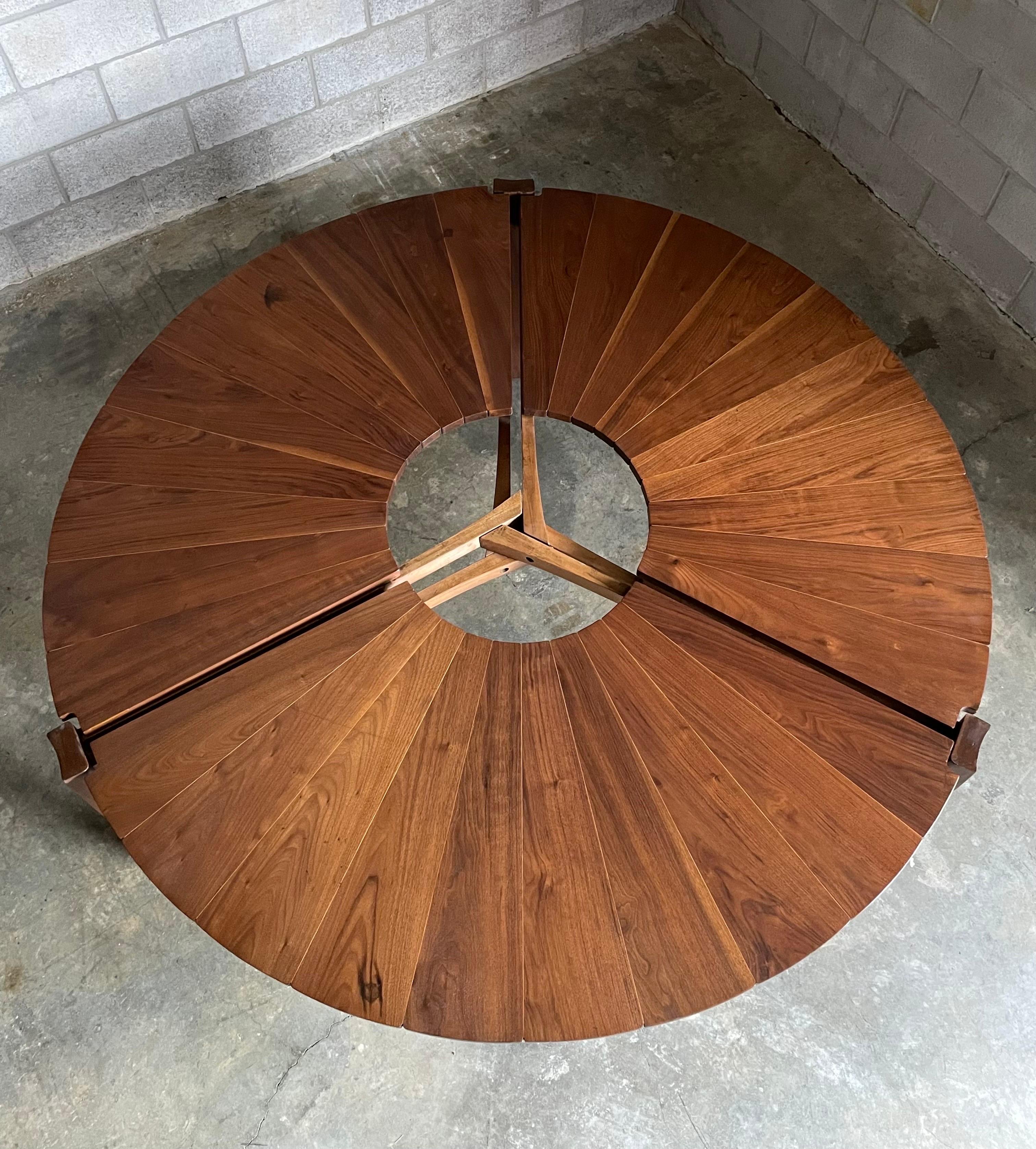 An incredible, one of a kind, dining table designed and made by Charles Faucher in 1975. Table consists of three leg posts with a section of walnut petals between each leg. Walnut petals are separated by thin pieces of maple adding to the dramatic