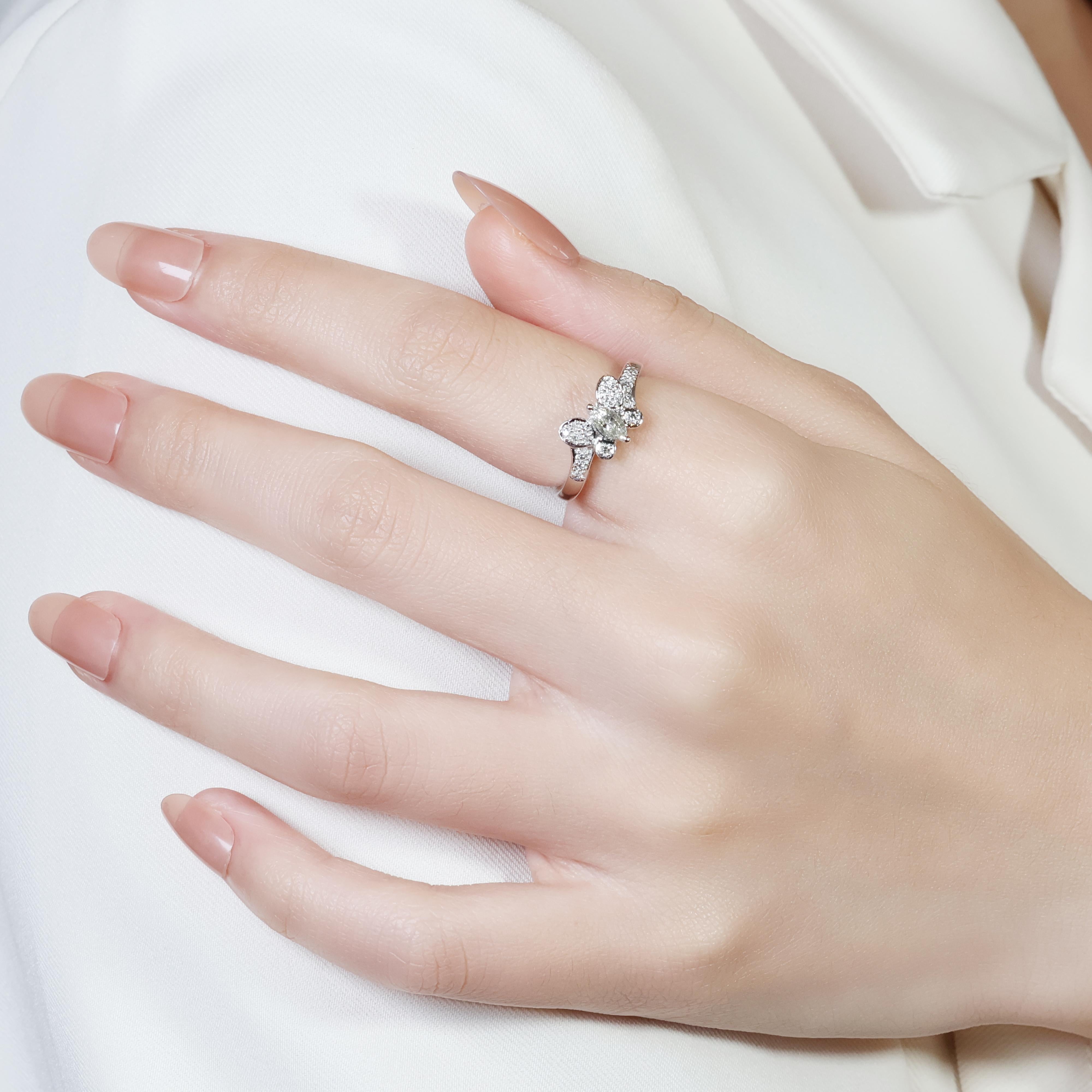 This stunning 18k white gold ring features a marquise cut diamond center stone boasting a weight of 0.22ct. The M color grade indicates a near-colorless stone, while the VS clarity signifies very slight inclusions that are undetectable to the naked