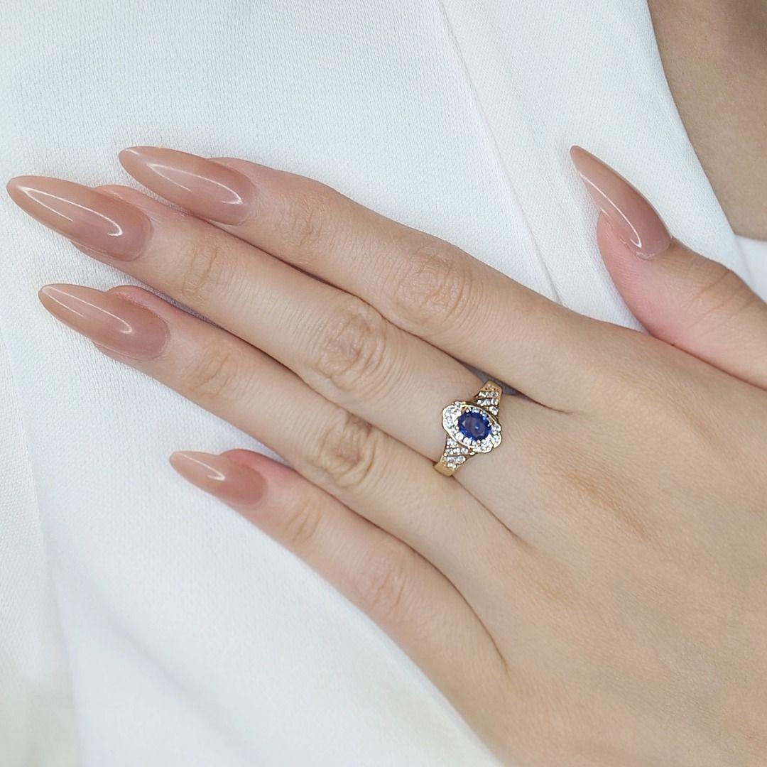 Réalisée en luxueux or jaune 18 carats, cette élégante bague est ornée d'un saphir ovale de 0,28 carats à la teinte bleue vibrante en son centre, dégageant un charme intemporel. Le saphir est rehaussé de 28 diamants ronds naturels de taille