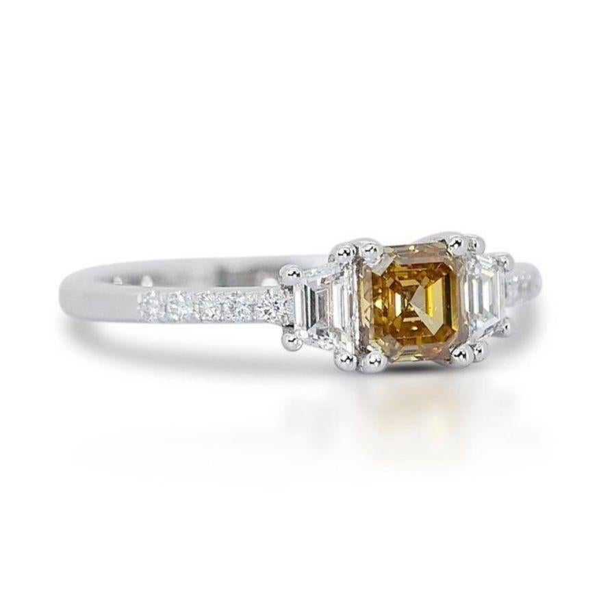 Own the spotlight with this dazzling ring, a symphony of captivating warmth frozen in 1.11 total carats. The square modified brilliant diamond, ablaze with Natural Fancy Deep Orange Yellow color, commands attention with its bold beauty, mirrored by