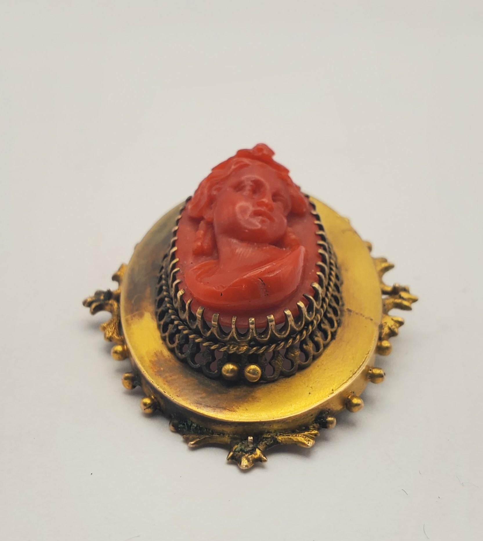 Gorgeous 14k yellow gold and Mediterranean coral cameo convertible pendant/brooch. This antique piece features a lady with elaborate curly hair in right-facing quarter profile position. The bold vermillion color of the Mediterranean coral looks