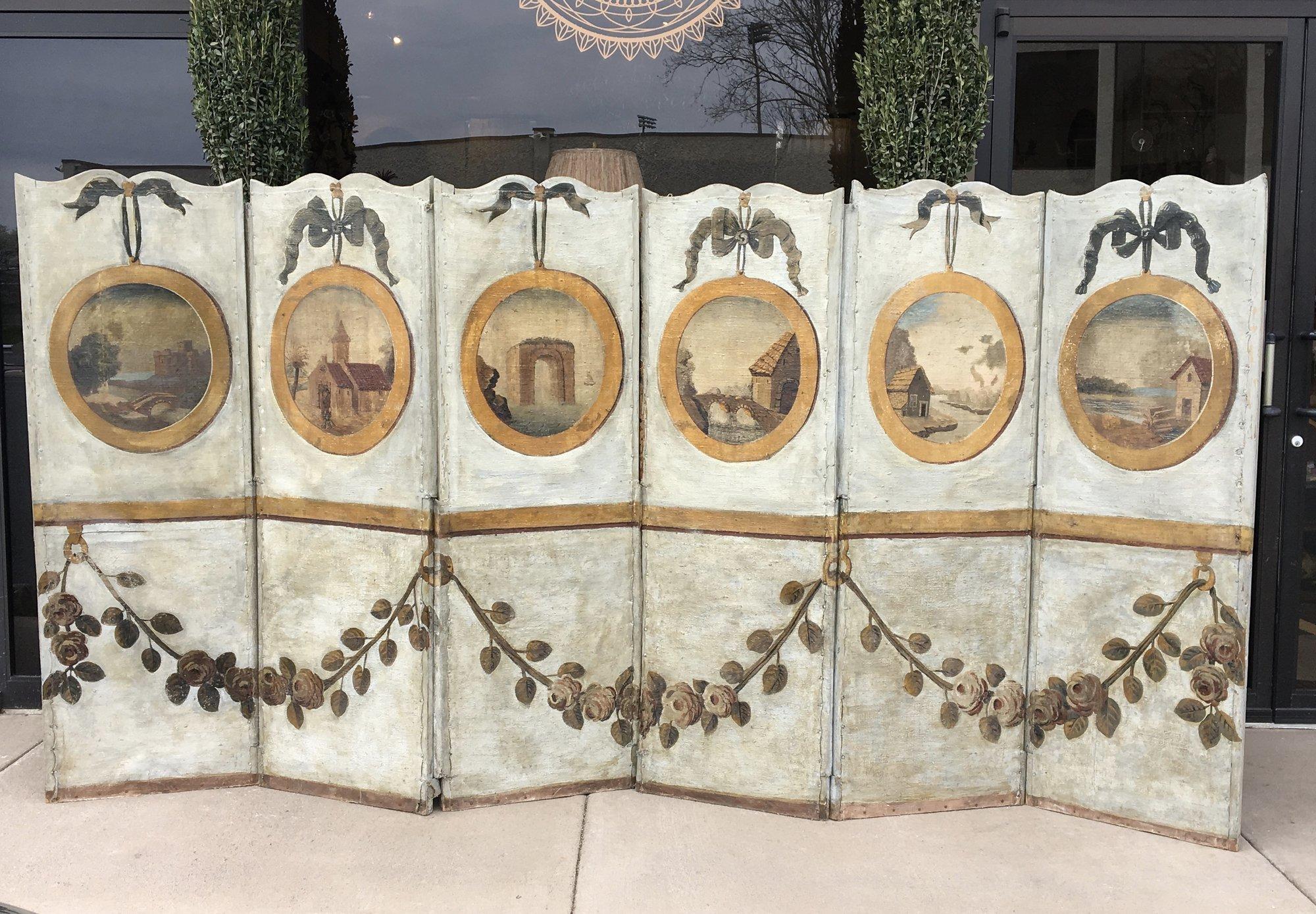 A rare 18th century French Provincial 6-panel screen, oil paint on canvas, with landscapes featured in medallion cartouches and a foliate design on the bottom half. A charming piece in pale green/grey, mustard and olive tones, 123” wide when fully