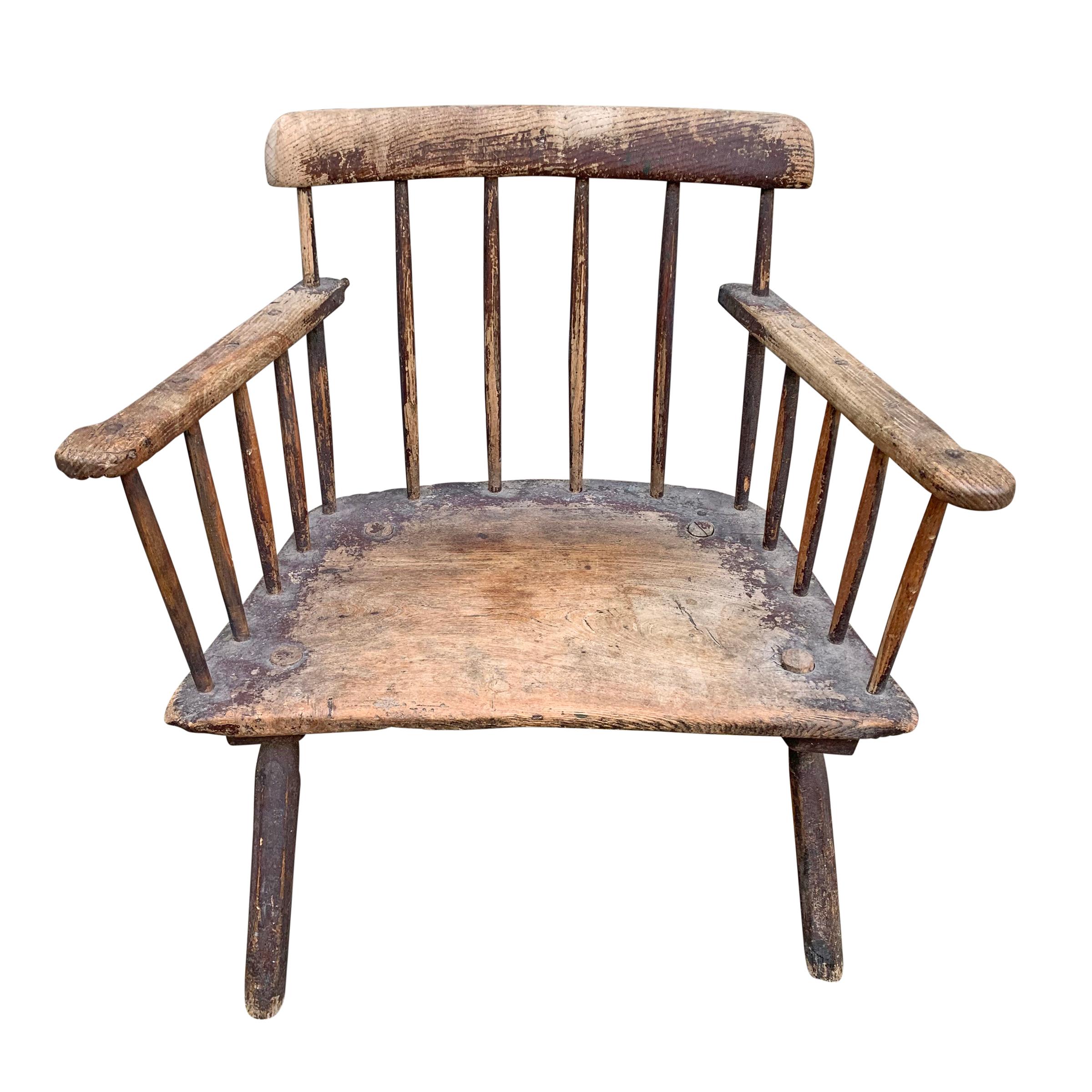 A stunning 18th century Welsh vernacular comb-back Windsor chair of simple design with well-worn out-turned arms, a solid plank seat with through pegged legs, and traces of the original painted finish. Chairs of this style were designed to be placed
